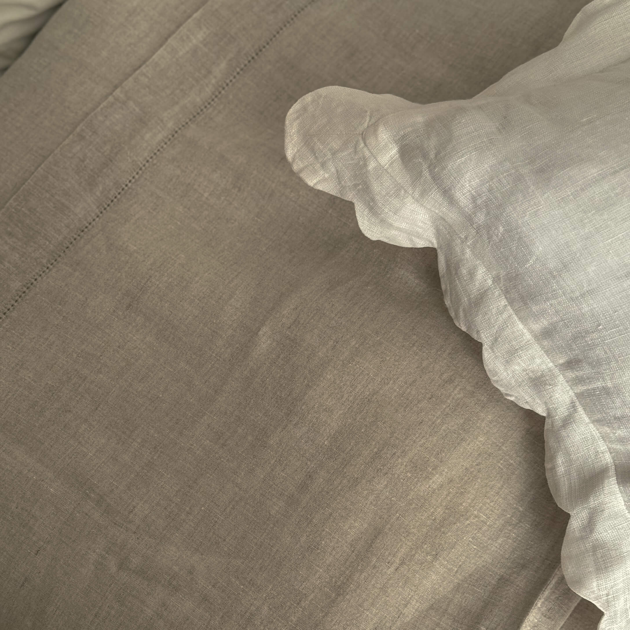 Linge de lit en lin beige et blanc avec texture naturelle pour une chambre confortable