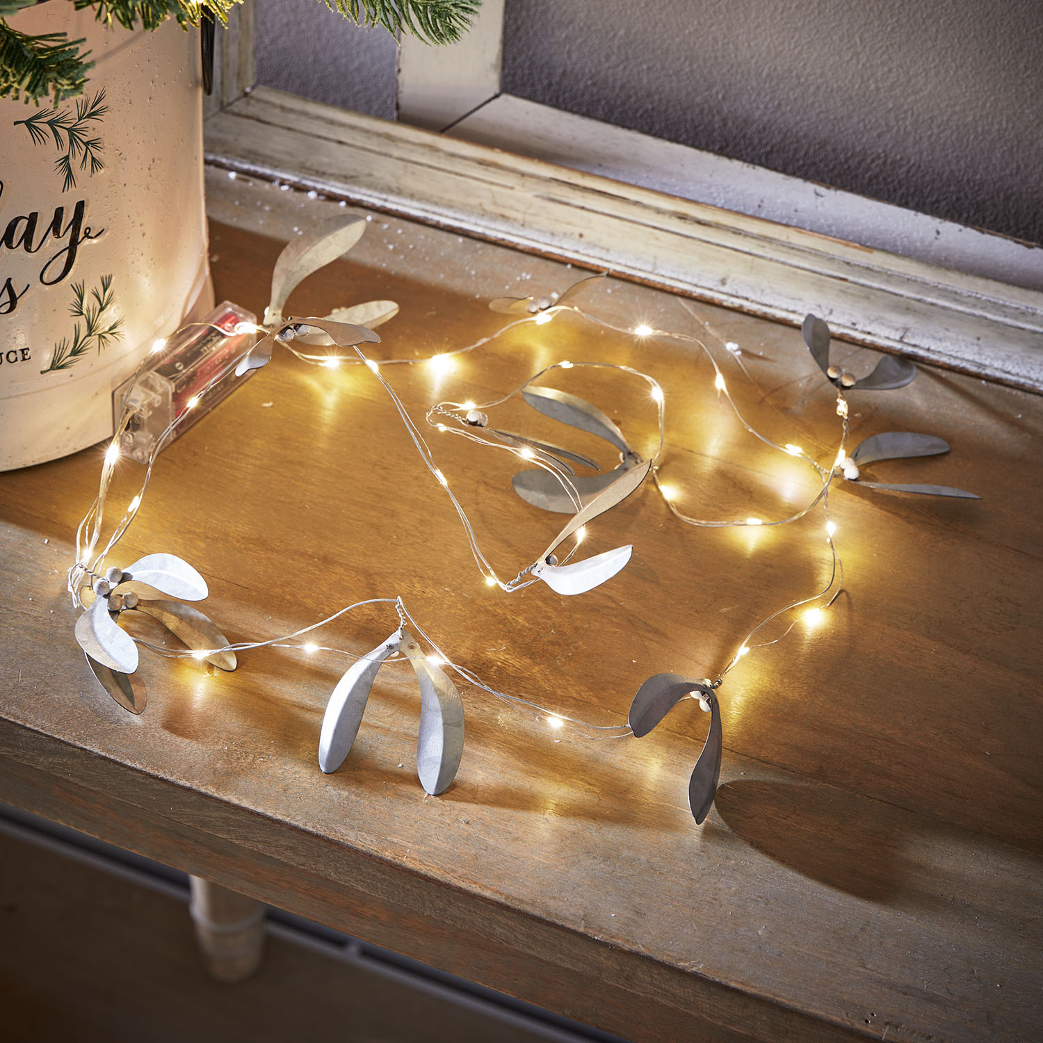 Fijne lichtsnoer met zilverkleurige metalen bladeren op houten tafel, sfeervolle kerstdecoratie