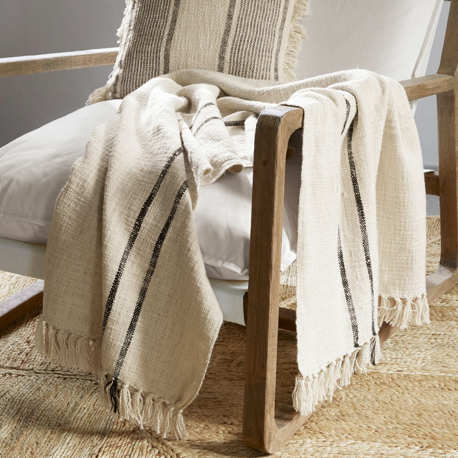 Beige katoenen plaid met zwarte strepen en franjes op houten stoel in woonkamer