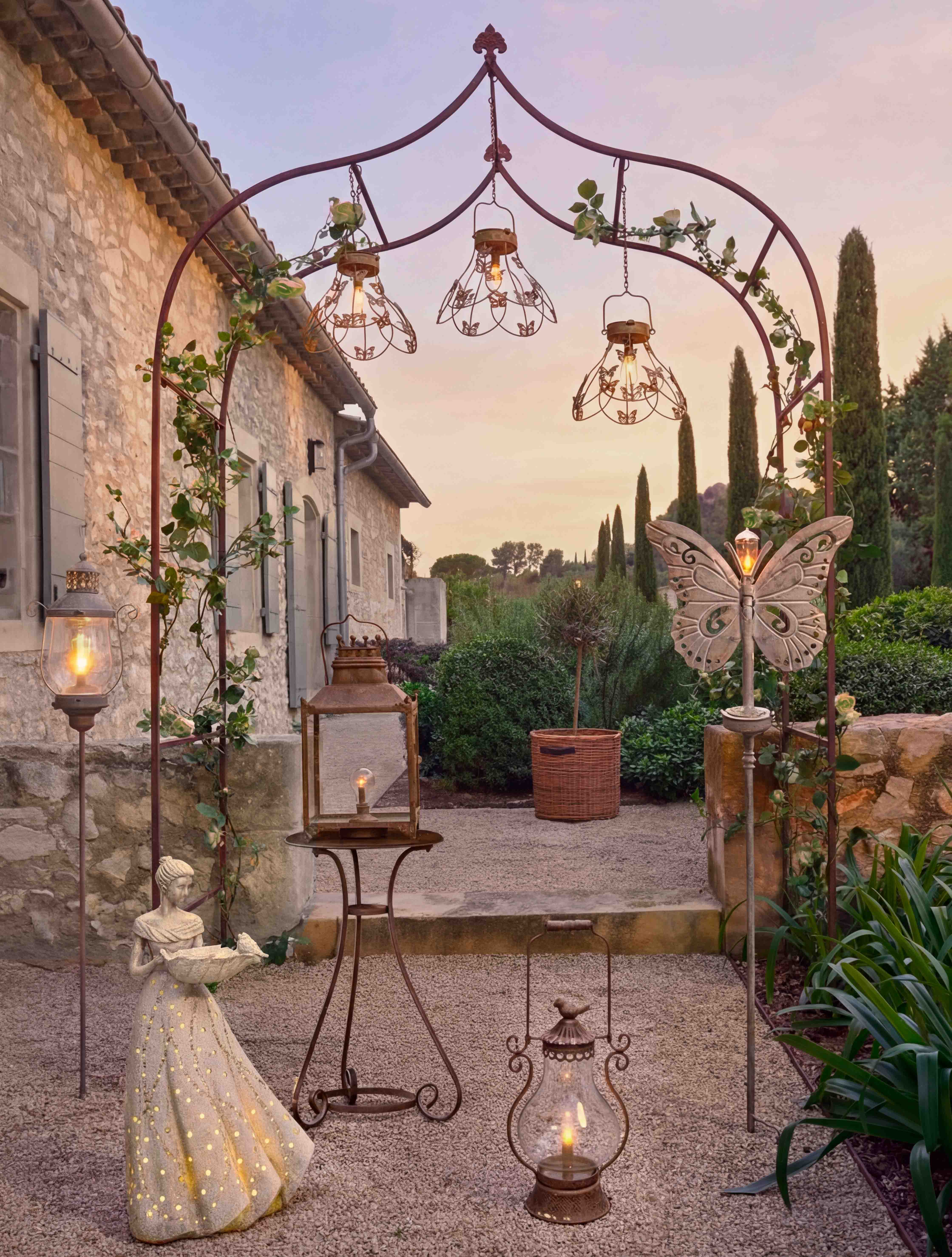 Decoratieve metalen boog met lantaarns en vrouwenfiguur verlicht in tuin bij schemering