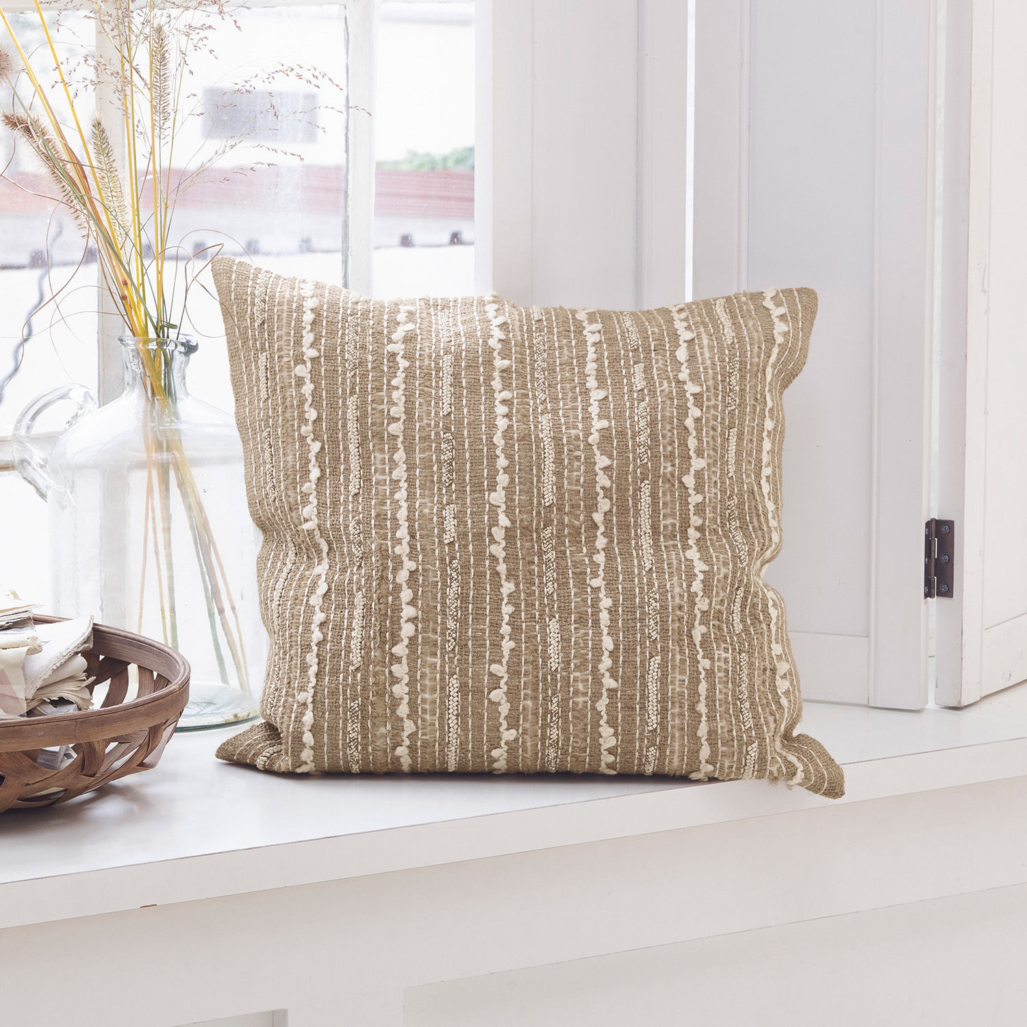 Coussin Ostendo Coussin décoratif beige avec motif texturé posé sur un rebord de fenêtre clair style bohème