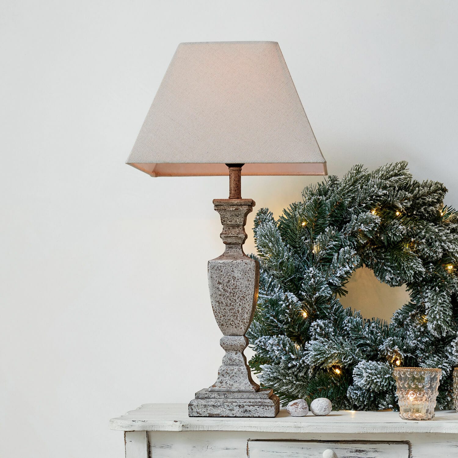 Tafellamp Gorham Beige stenen tafellamp met kap naast groene kerstkrans met lichtjes op witte tafel