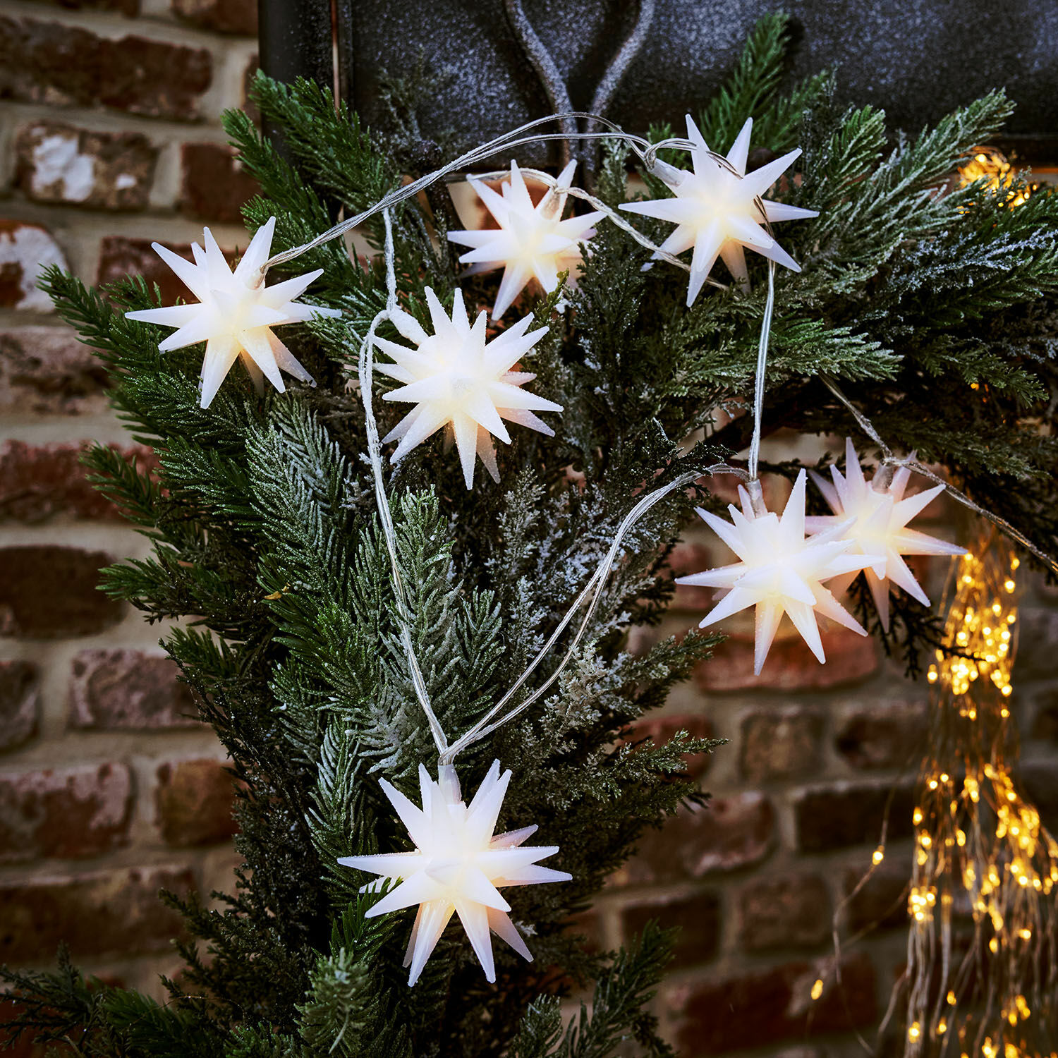 Lichtsnoer met witte sterren aan groene takken voor sfeervolle kerstdecoratie