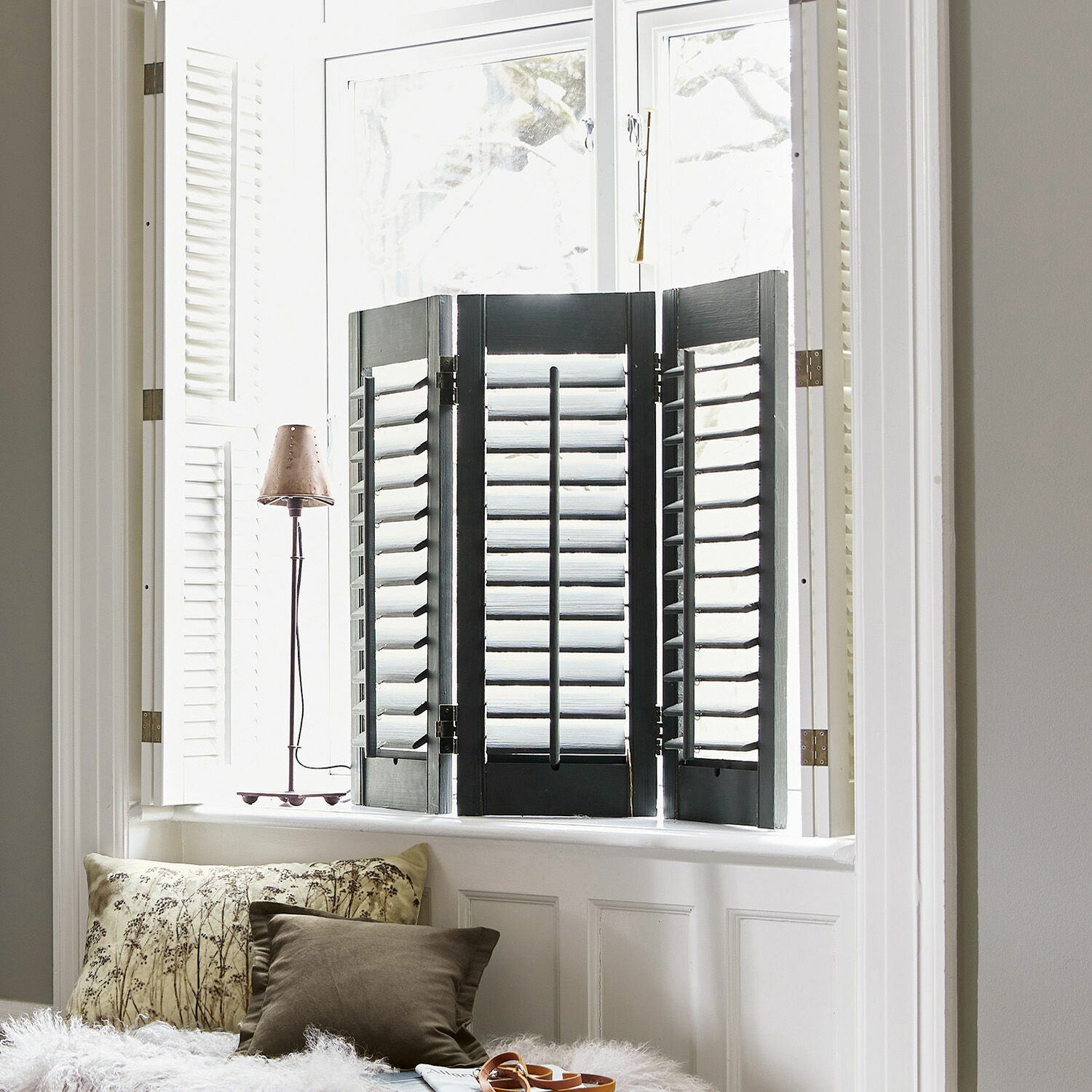 Shutter Ventura Zwarte houten shutters voor een helder raam met kussens en lamp op de vensterbank