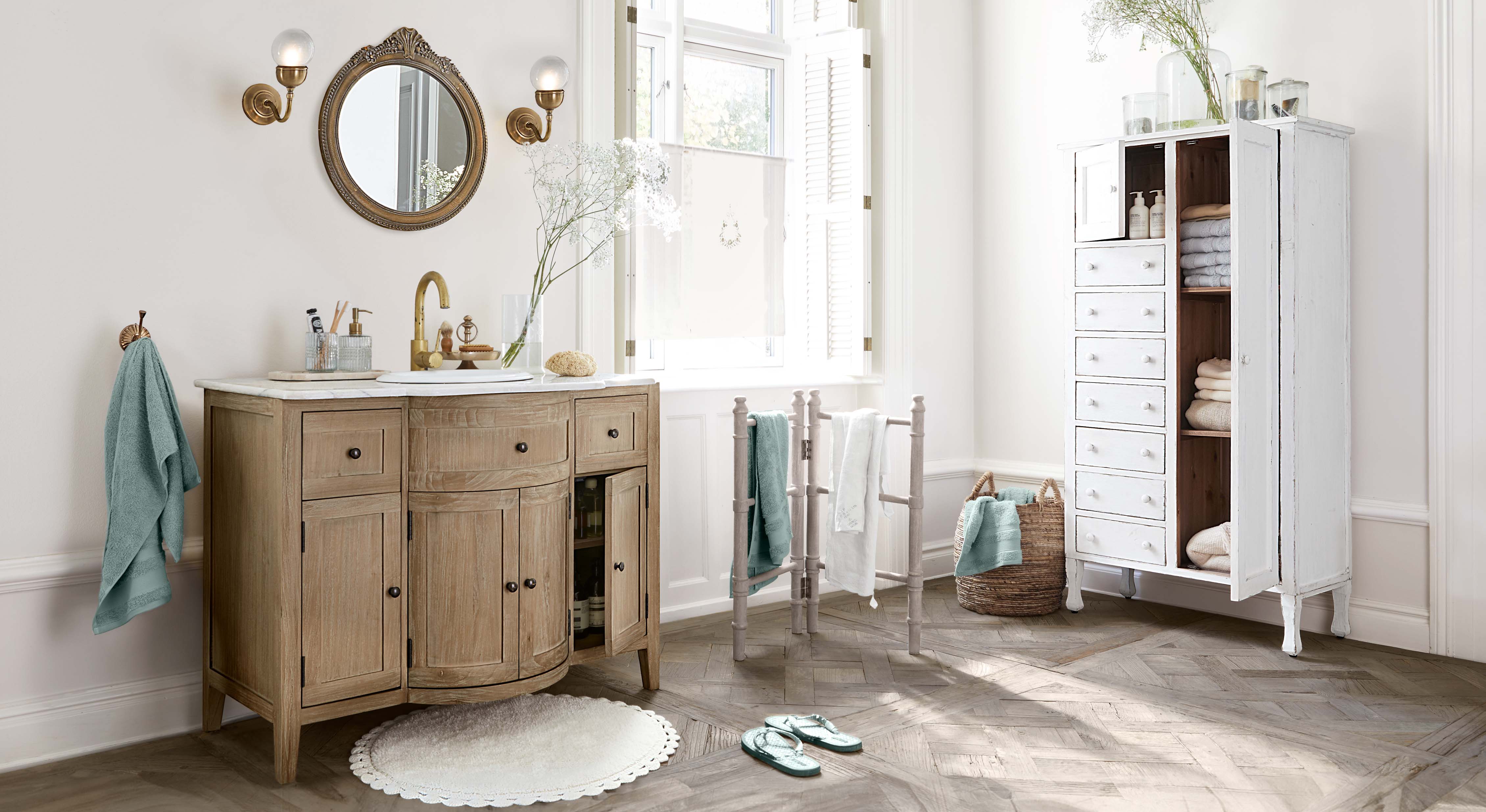 Salle de bain avec meuble sous-vasque en bois, armoire blanche et serviettes turquoise, ambiance lumineuse naturelle