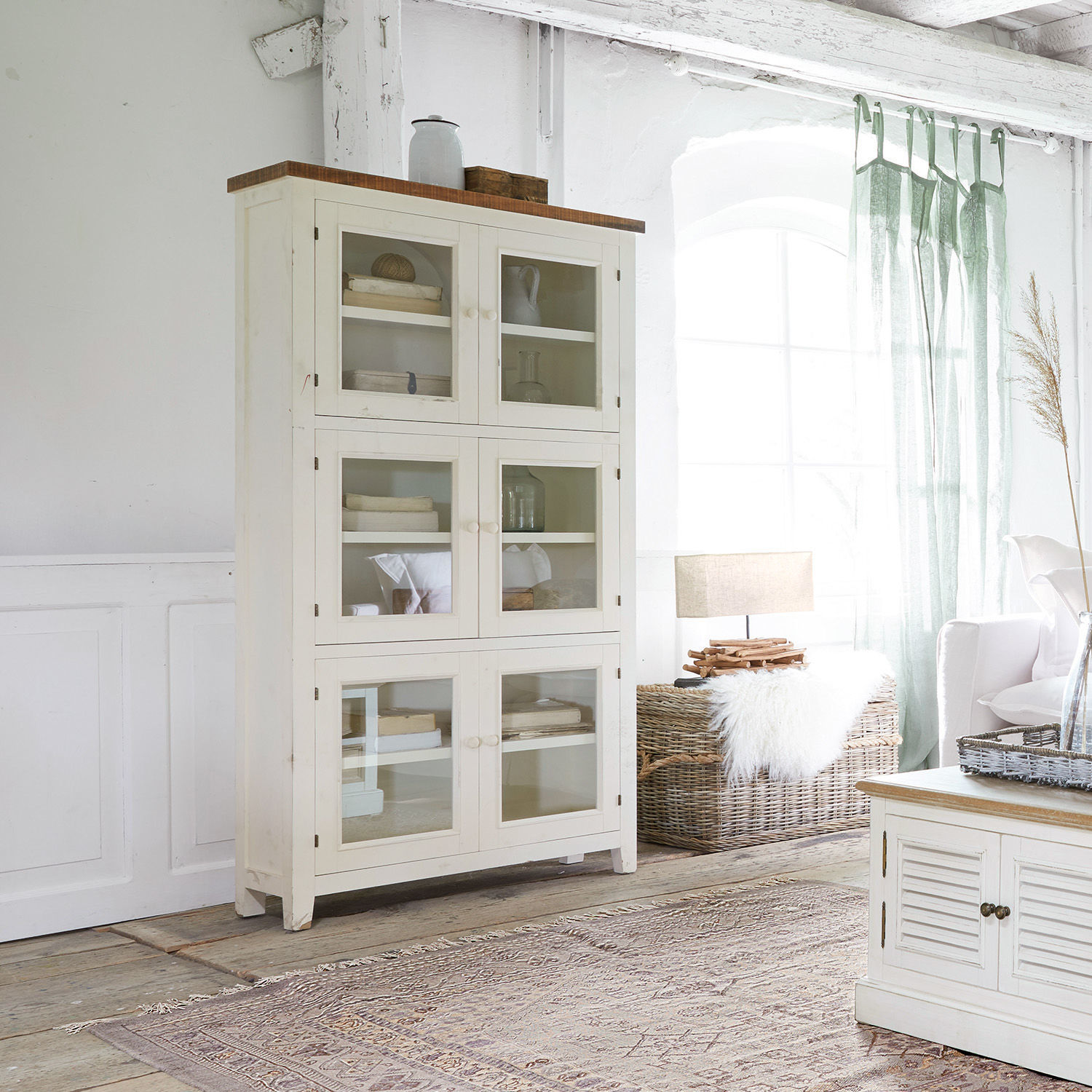 Vitrine Yukon Vitrine en bois blanc avec portes vitrées dans un salon lumineux au style naturel