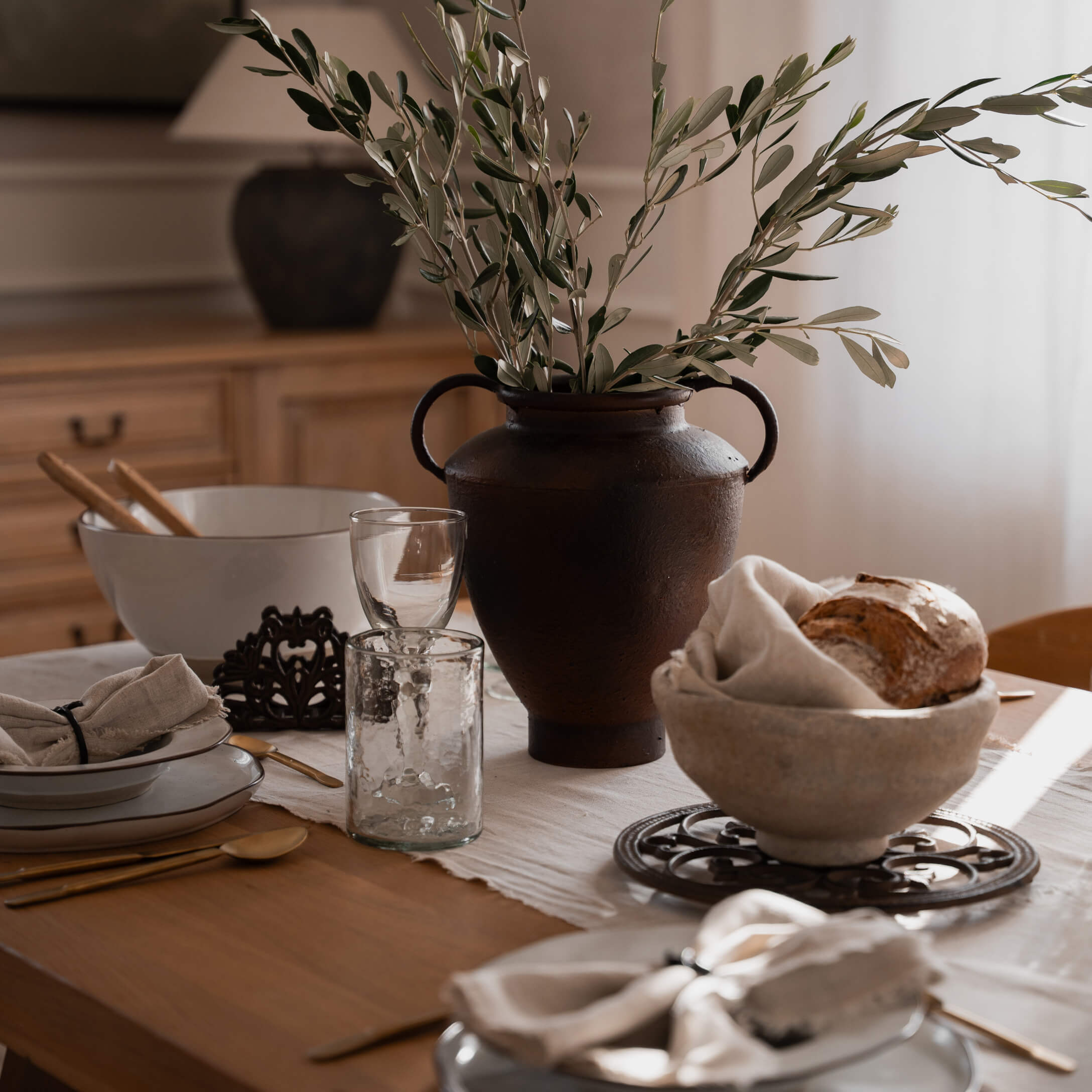 Rustieke bruine keramische vaas met groene takken op houten tafel met servies
