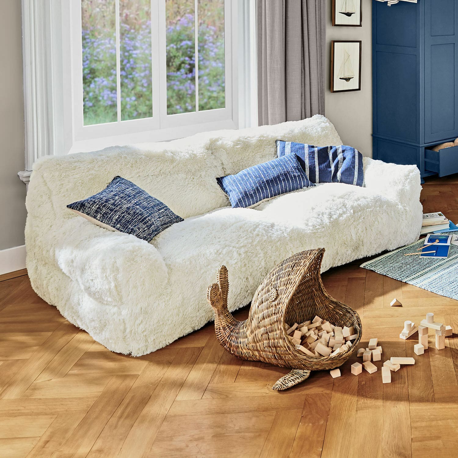 Kinderbank Cerveteri Witte, zachte pluche bank met blauwe kussens in lichte woonkamer met houten vloer