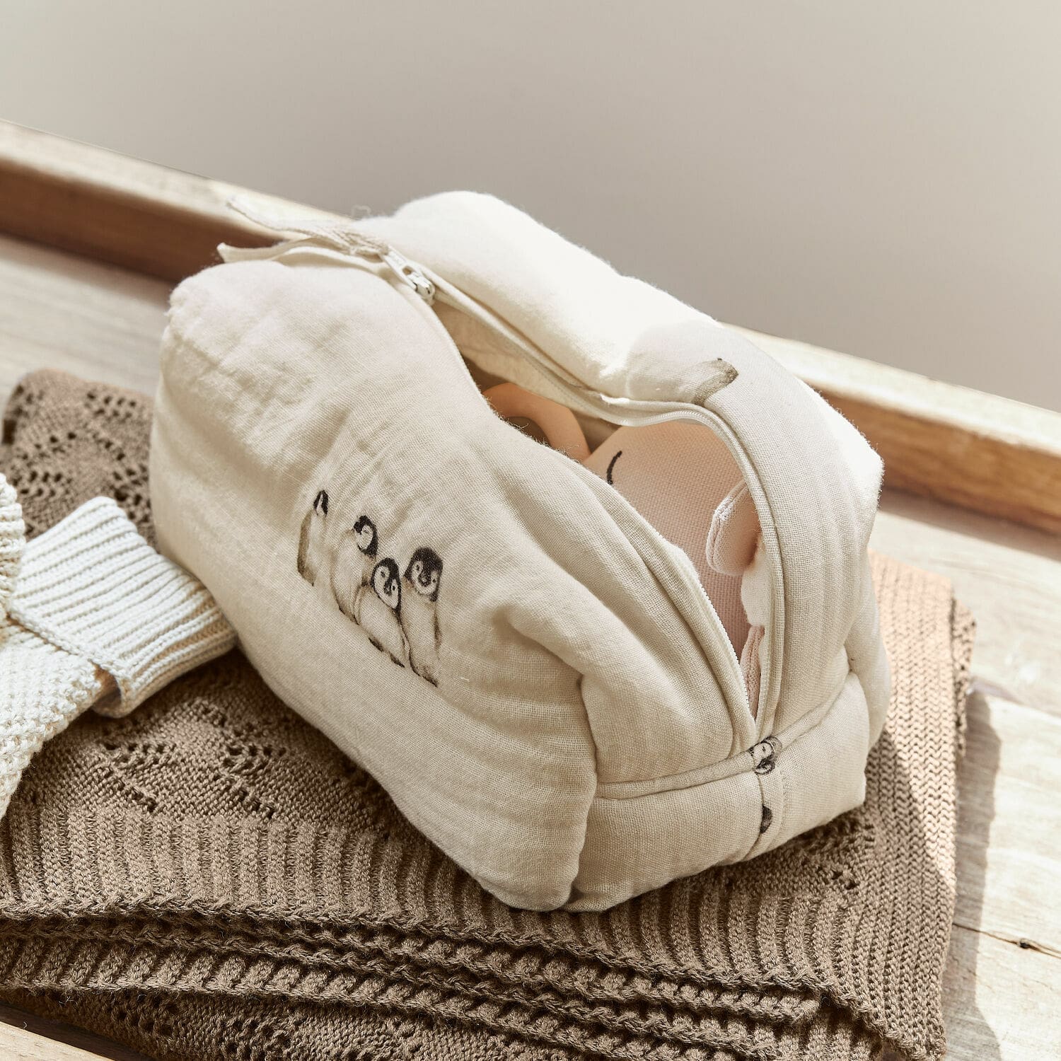 Tasje Jocienne Beige katoenen toilettas met pinguïnprint op bruine gebreide achtergrond, praktische opbergtas