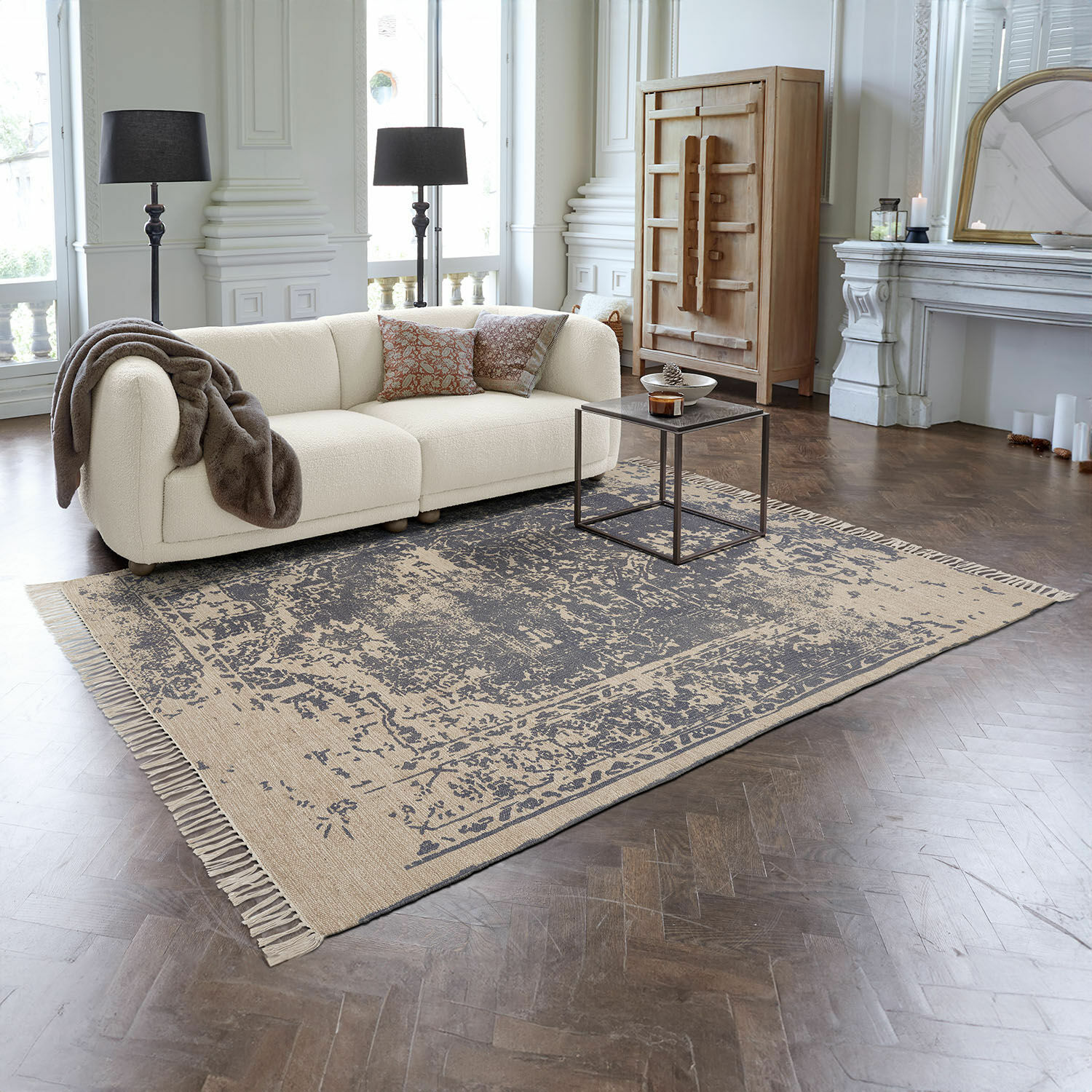 Beige vloerkleed met donkerblauw patroon en franjes op houten vloer in moderne woonkamer