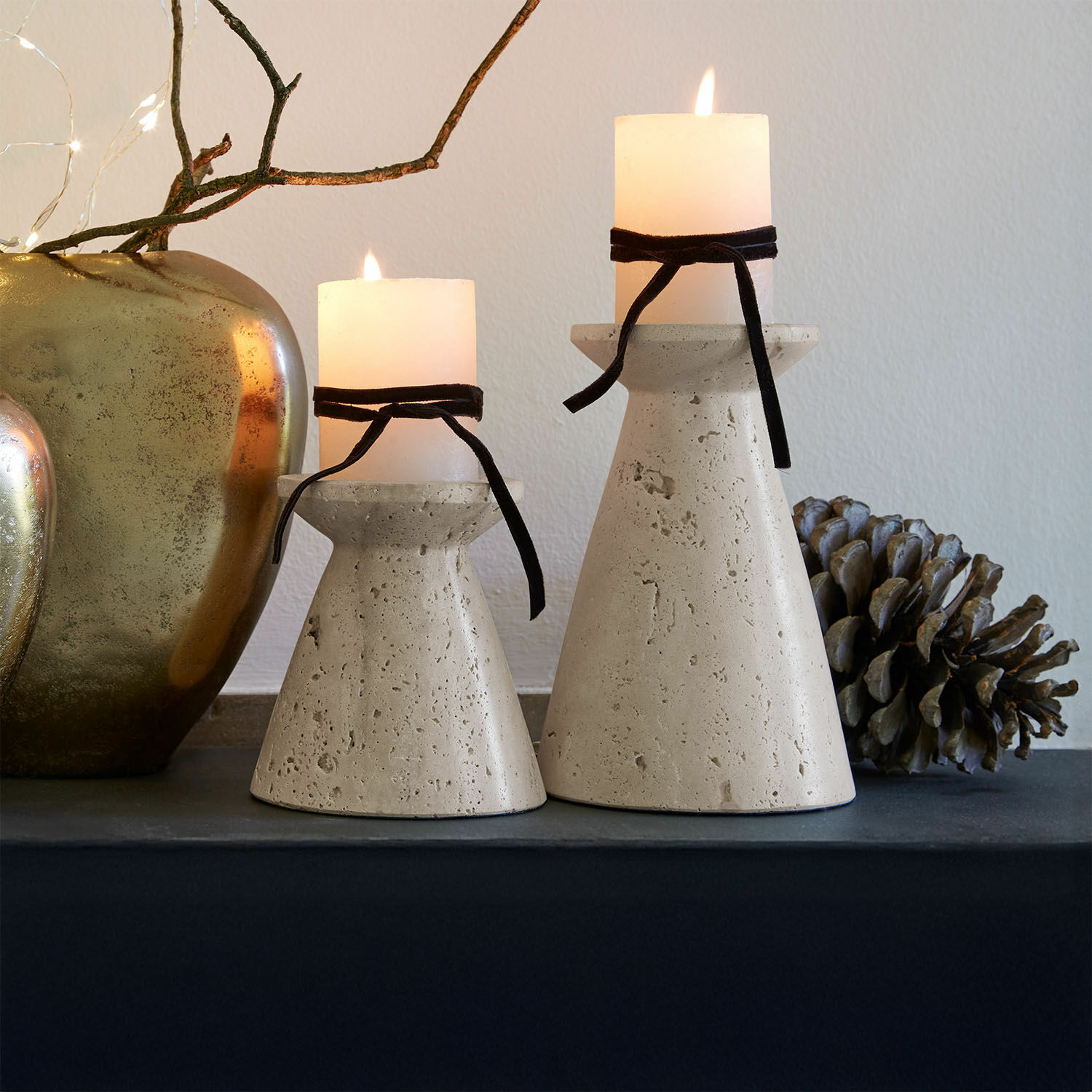 Lot de 2 bougeoirs Bazrahim Deux bougeoirs en béton beige avec bougies blanches et rubans noirs sur une table décorative