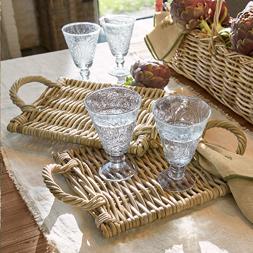 Deux verres en verre gravé sur un plateau en osier avec poignées sur une table en tissu