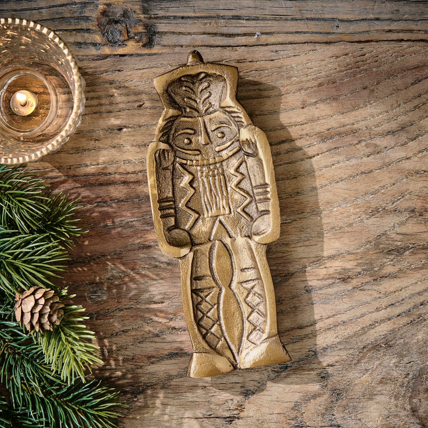Coupelle Zarilith Figurine décorative en métal doré posée sur une table en bois avec branche de sapin et bougie