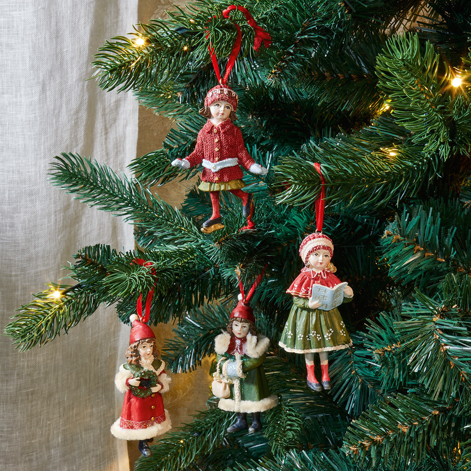 Set van vier kerstboomversieringen met figuurtjes van kinderen in rode en groene winterkleding