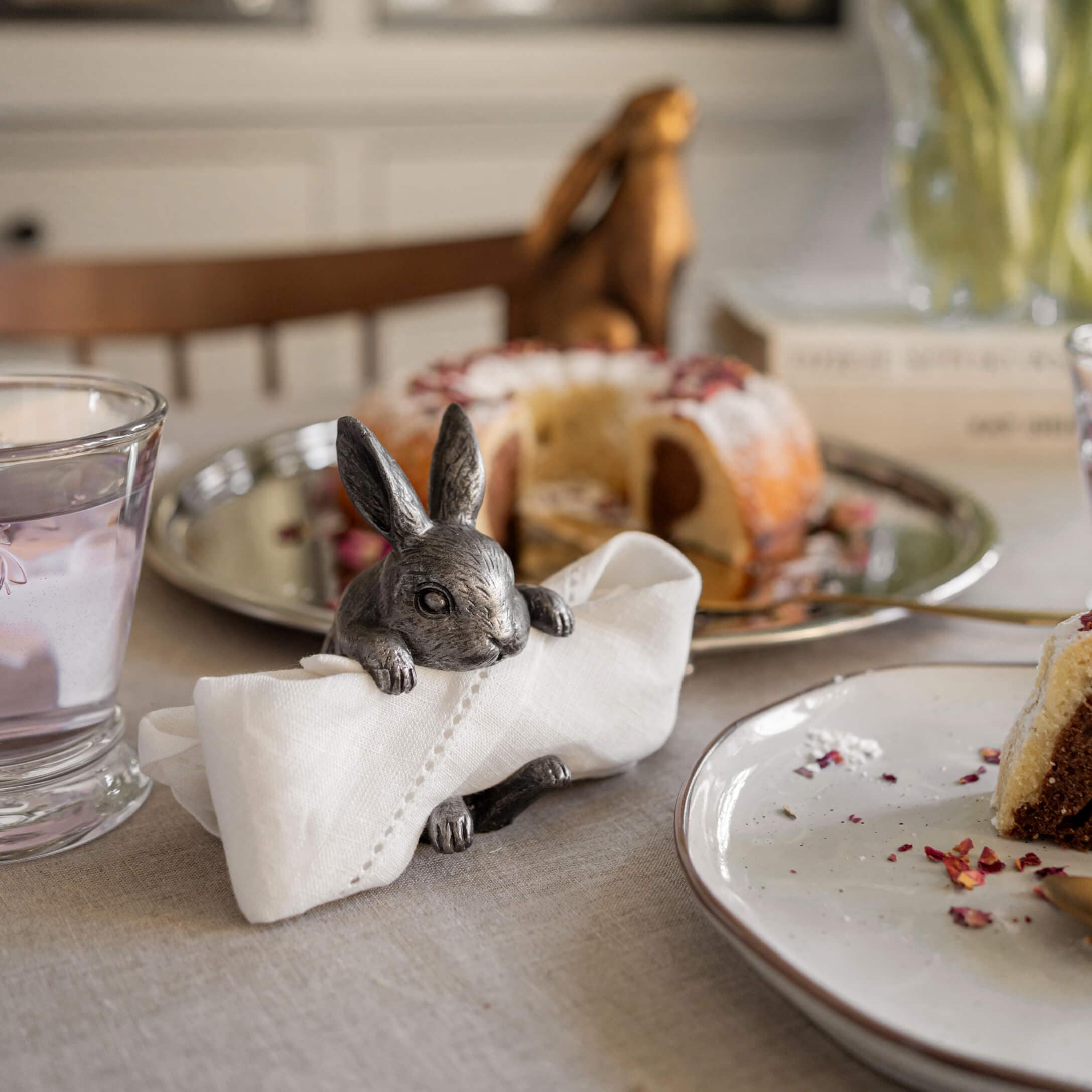 Porte-serviette en métal en forme de lapin sur table avec gâteau et verre d'eau