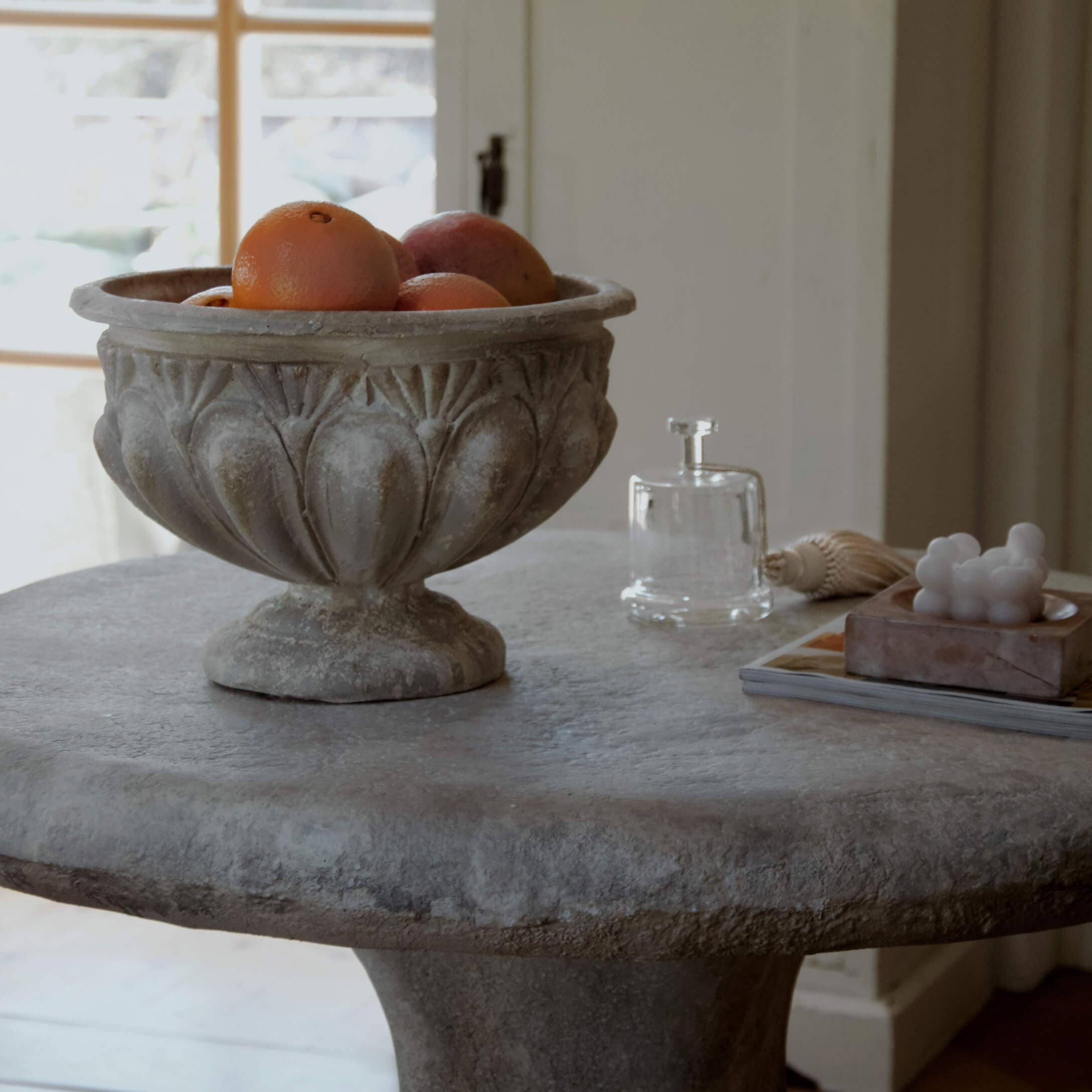 Coupe décorative en pierre avec des oranges sur une table en pierre dans un intérieur lumineux