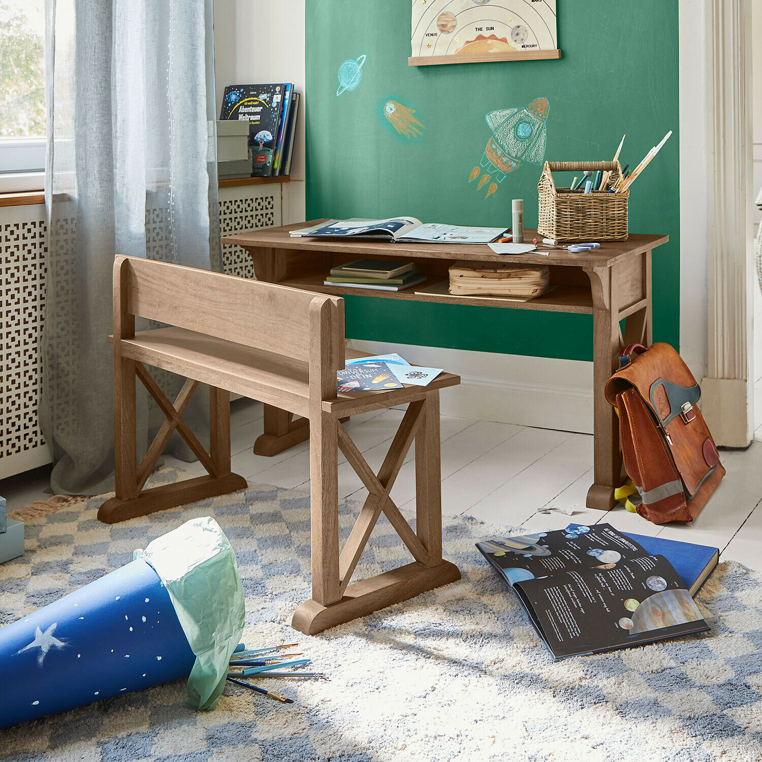 Bureau et banc en bois naturel dans une chambre d'enfant décorée sur le thème de l'espace avec livres éducatifs