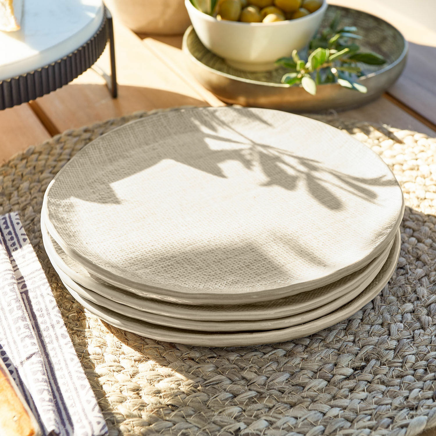Dessertbordje set van 4 Luganville Set crèmekleurige keramische borden met structuur op een gevlochten placemat van hout