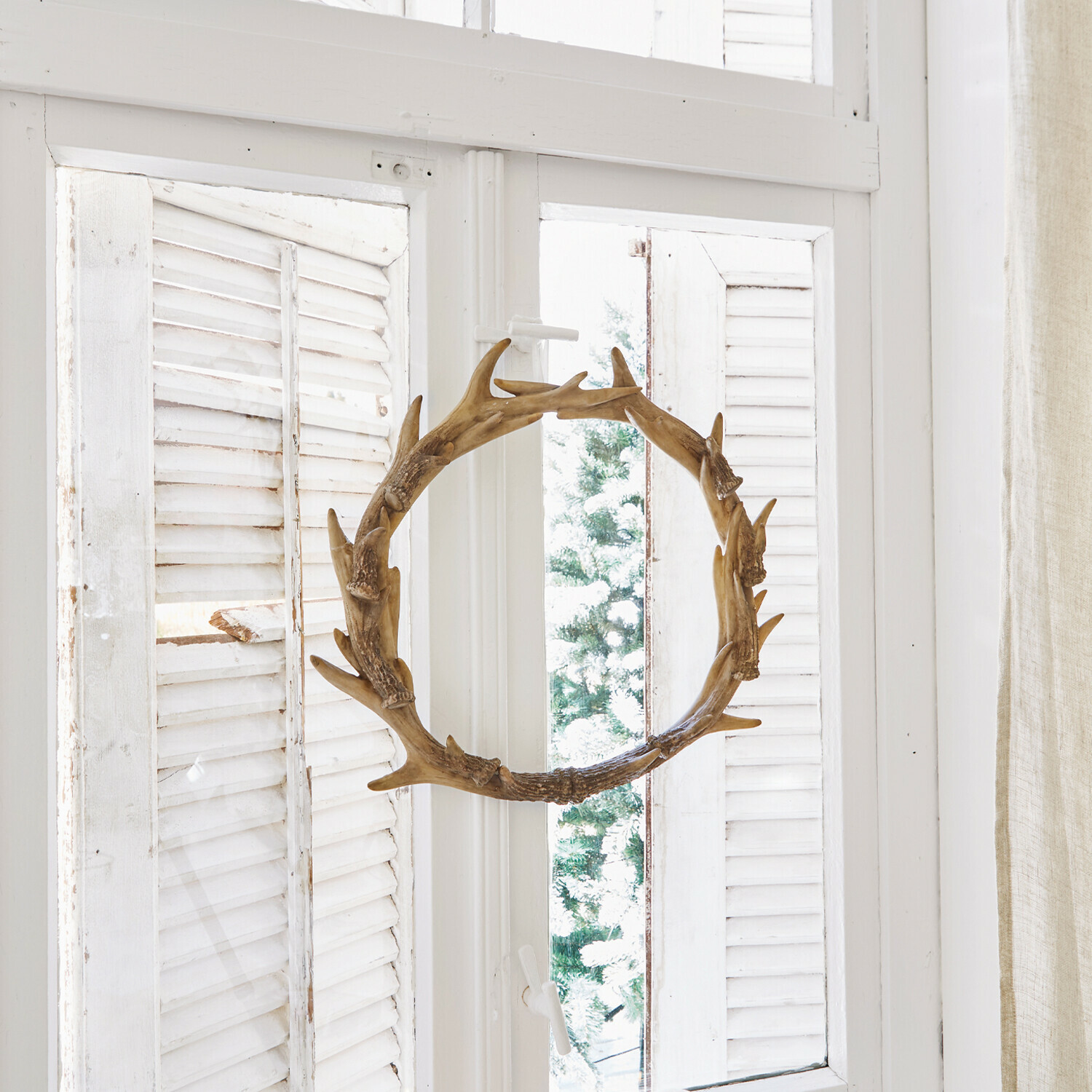 Couronne Marcelle Couronne décorative en bois en forme de bois de cerf sur fenêtre blanche avec bougies et pommes de pin