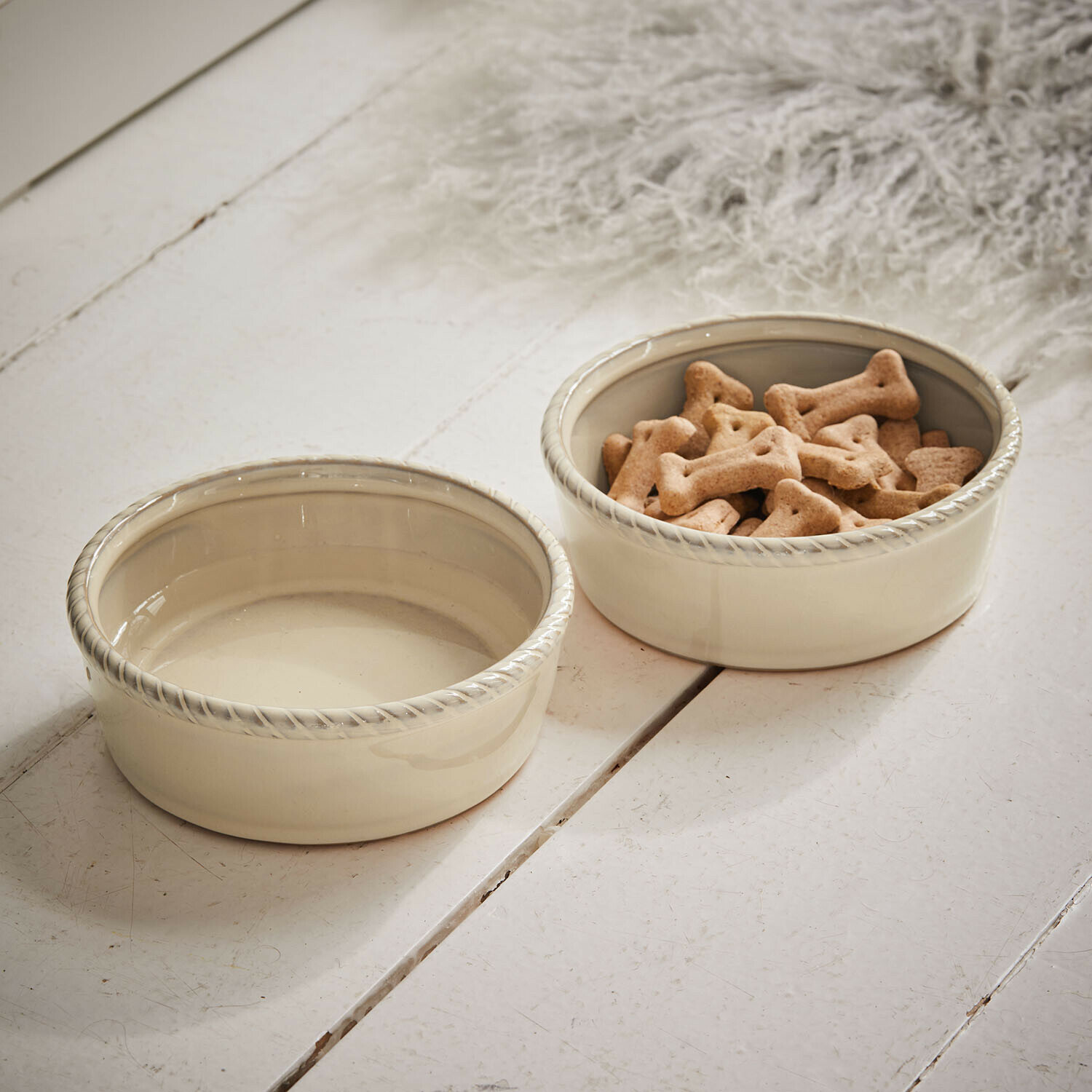 Lot de 2 gamelles Pawilo Deux bols en céramique crème pour chien avec bord décoratif posés sur un sol en bois blanc