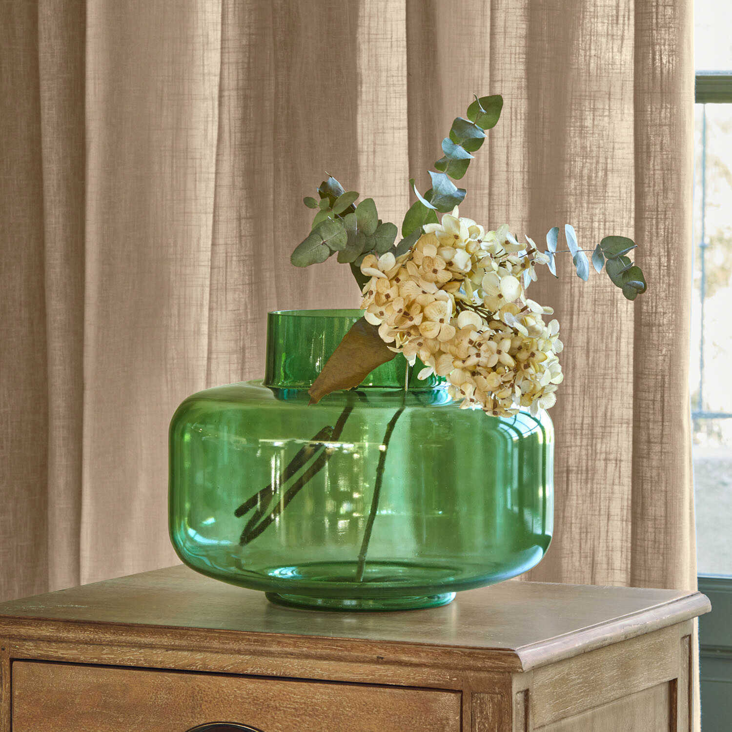 Vaas Ésmarine Groene glazen vaas met crèmekleurige bloemen op houten tafel, interieurdecoratie