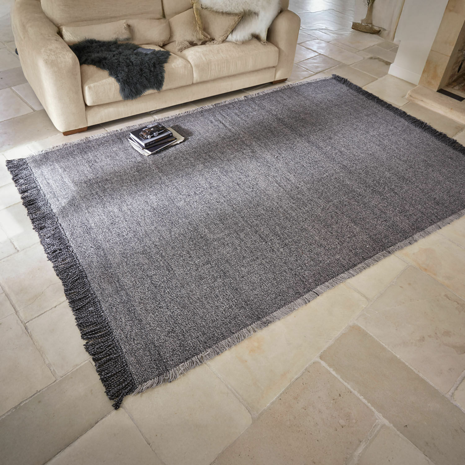 Tapis d’intérieur et d’extérieur Marivela Tapis gris à franges sur sol clair dans un salon avec canapé beige et coussins décoratifs