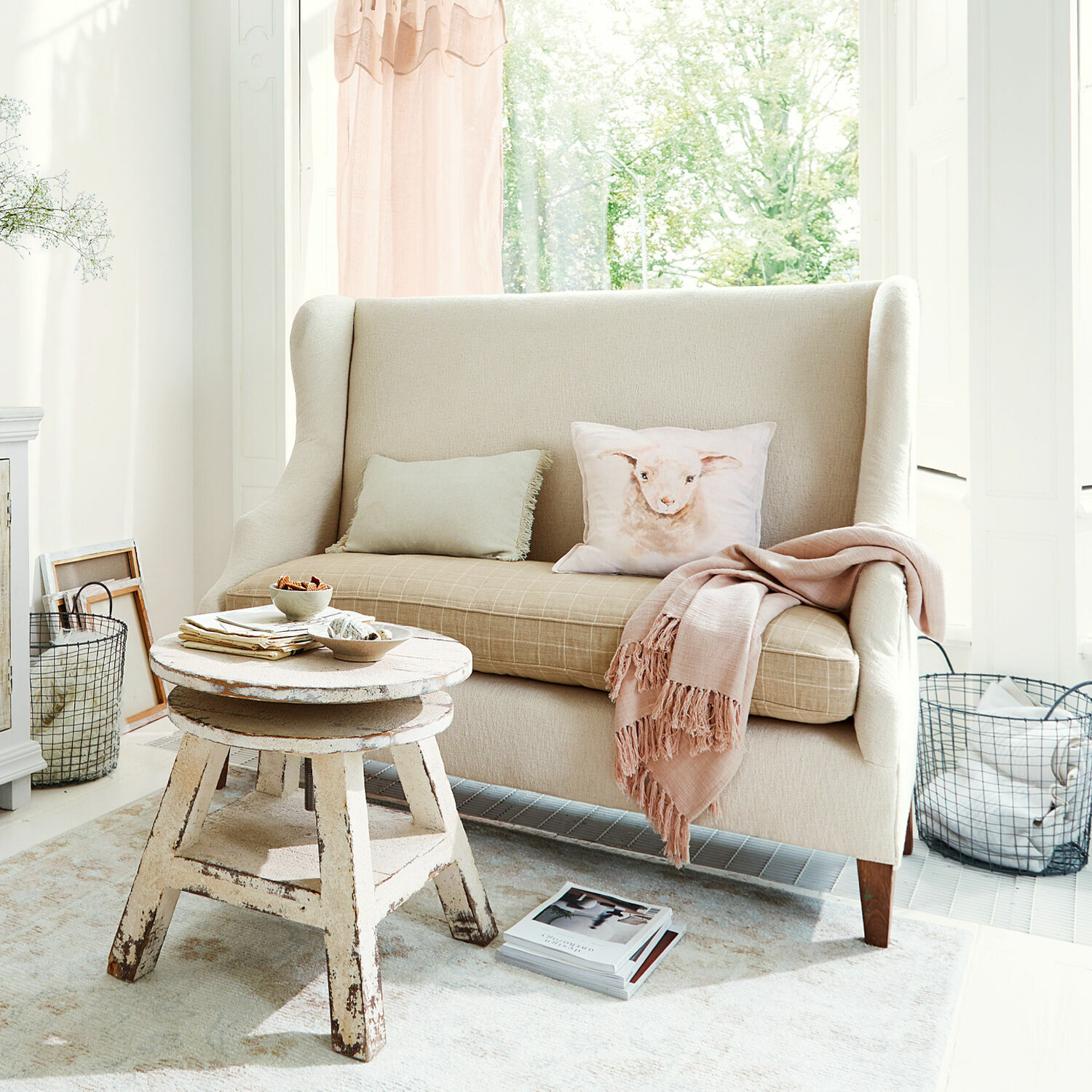 Bank Ombra Beige stoffen bank met kussen met lammetjesmotief en rustieke houten salontafel in lichte kamer