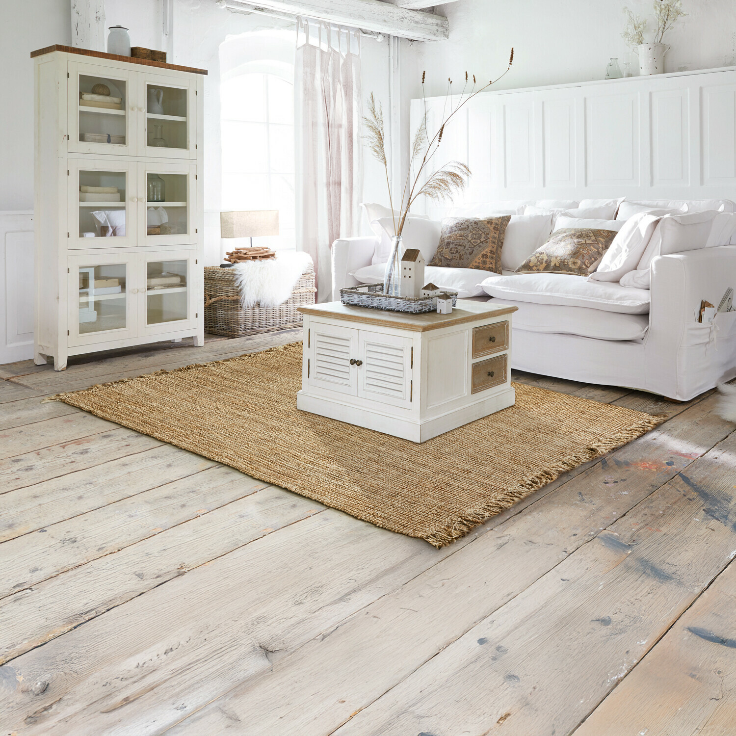 Vloerkleed Hermitage Lichte woonkamer met witte bank, lichte houten kast en natuurlijke jute vloerkleed in rustieke stijl