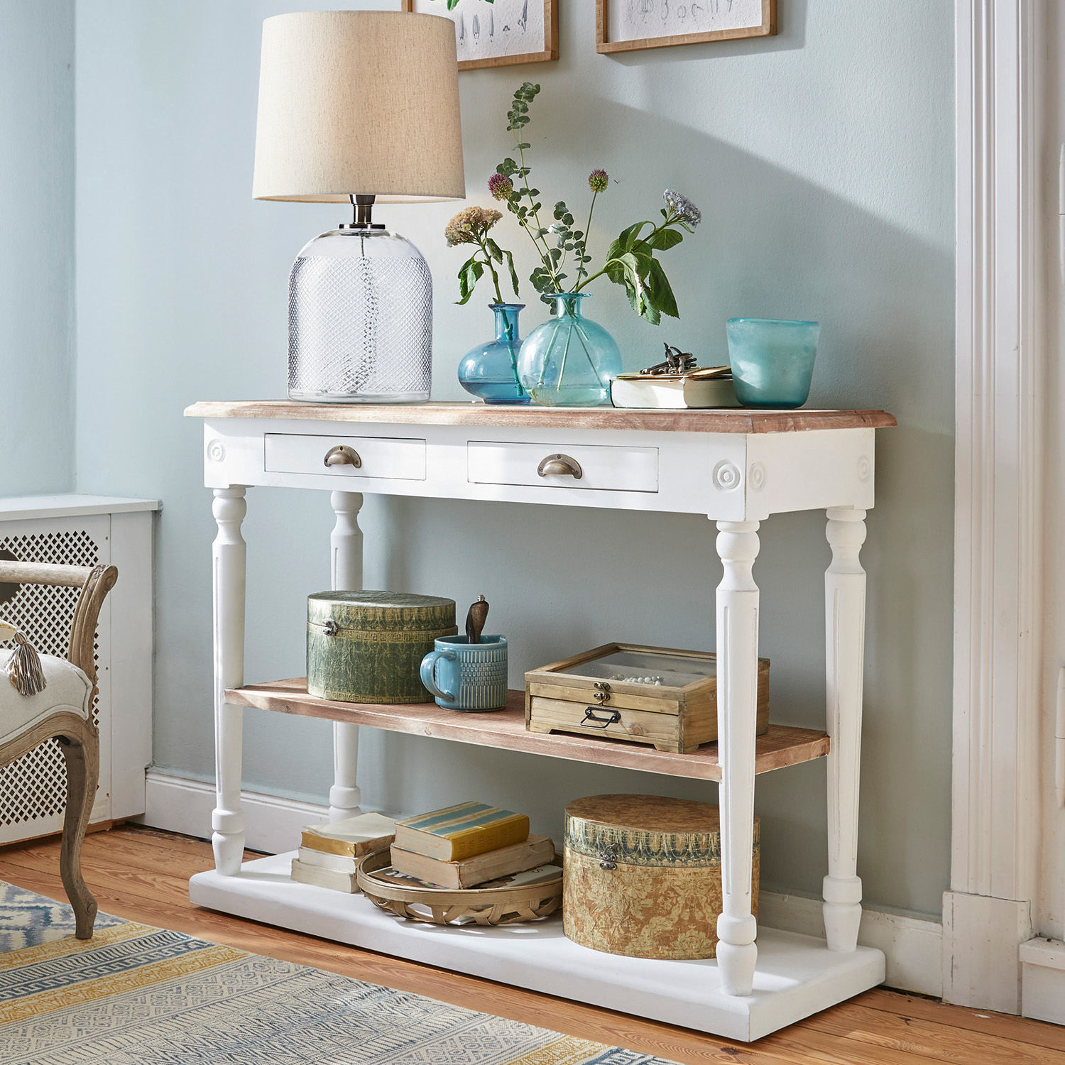 Console en bois blanc avec tiroirs et étagères, décorée d'une lampe et de vases bleus