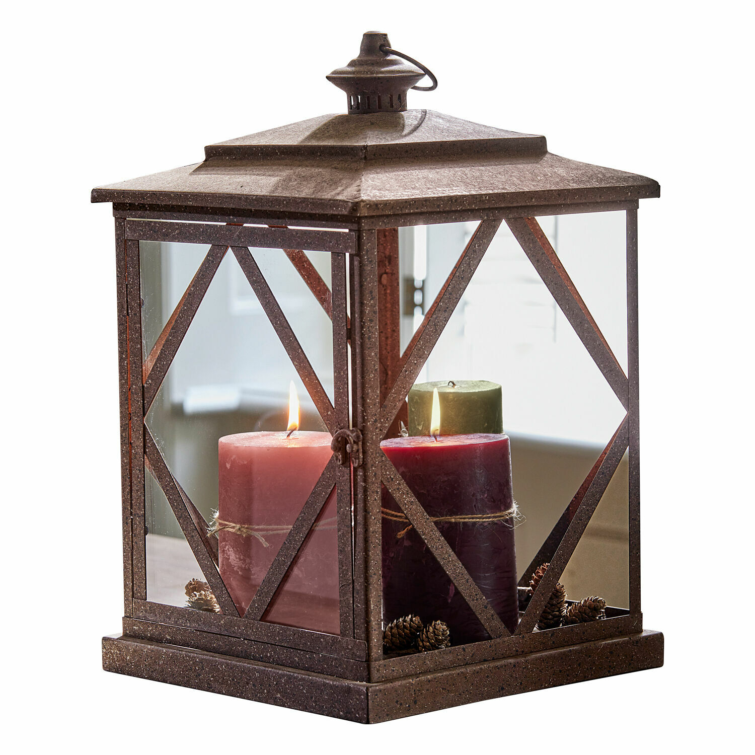 Bruine metalen lantaarn met drie brandende kaarsen en dennenappels binnenin