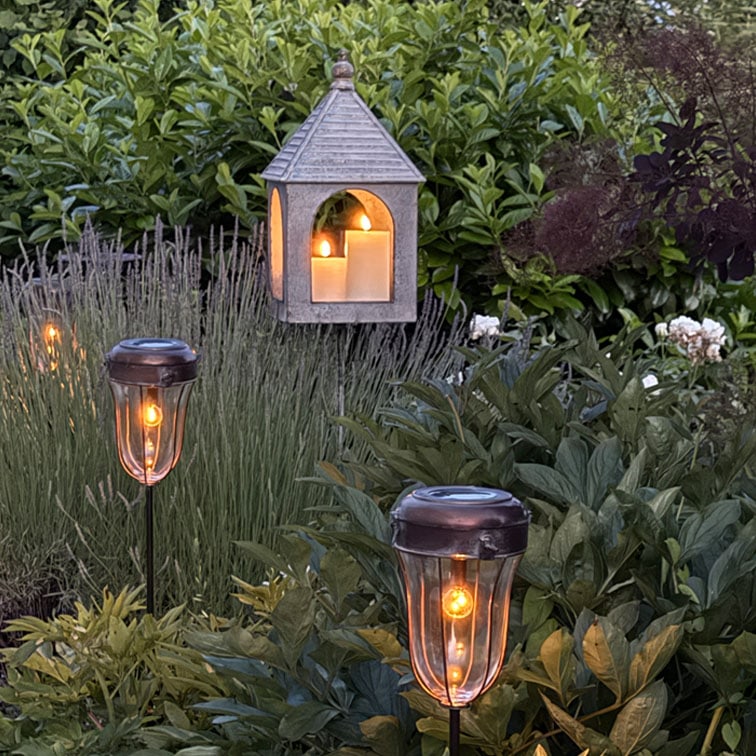 Jardin avec lampes solaires et lanterne suspendue avec bougies décoratives, éclairage extérieur