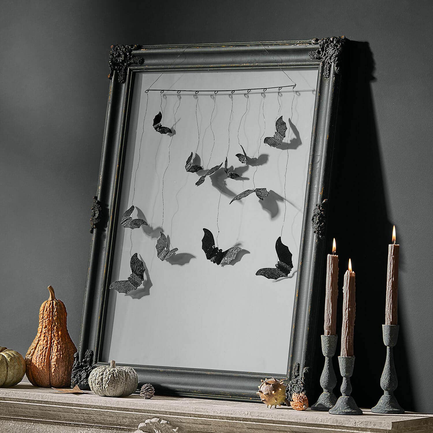 Cadre photo Zairouna Décoration murale avec chauves-souris en métal noir suspendues dans un cadre, citrouilles et bougies à côté