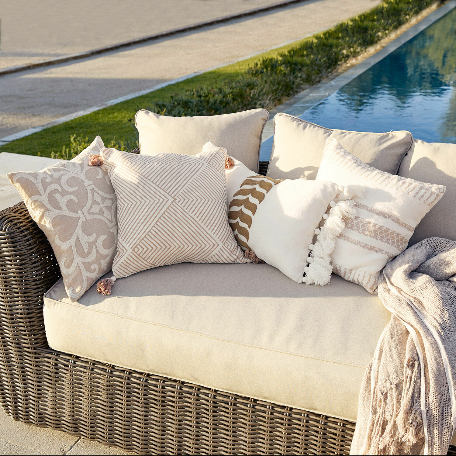 Lot de 4 housses de coussins Olette Canapé en rotin beige avec coussins décoratifs crème et beige à l'extérieur près de la piscine