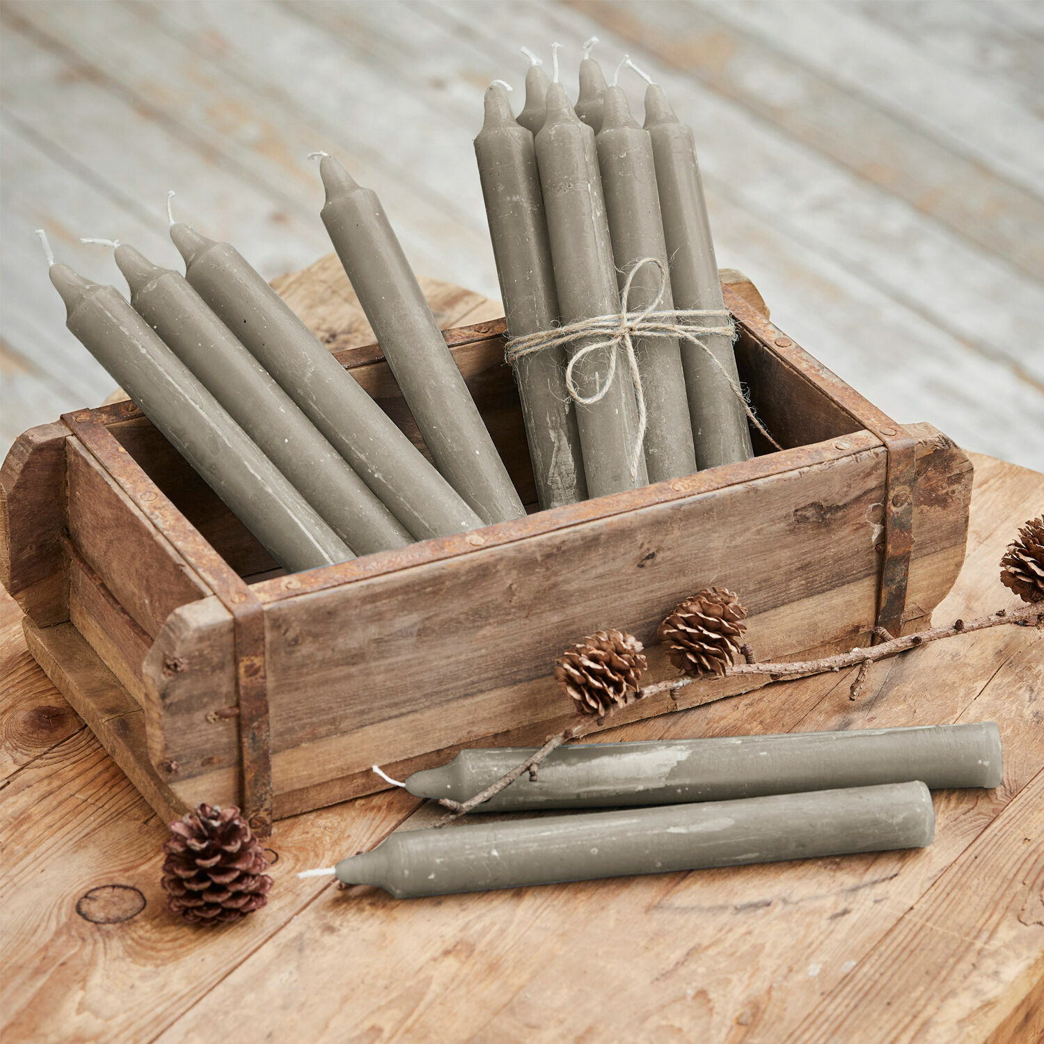 Kaars set van 12 Bauceau Grijze stompkaarsen van was in houten kist op rustieke houten tafel met dennenappels