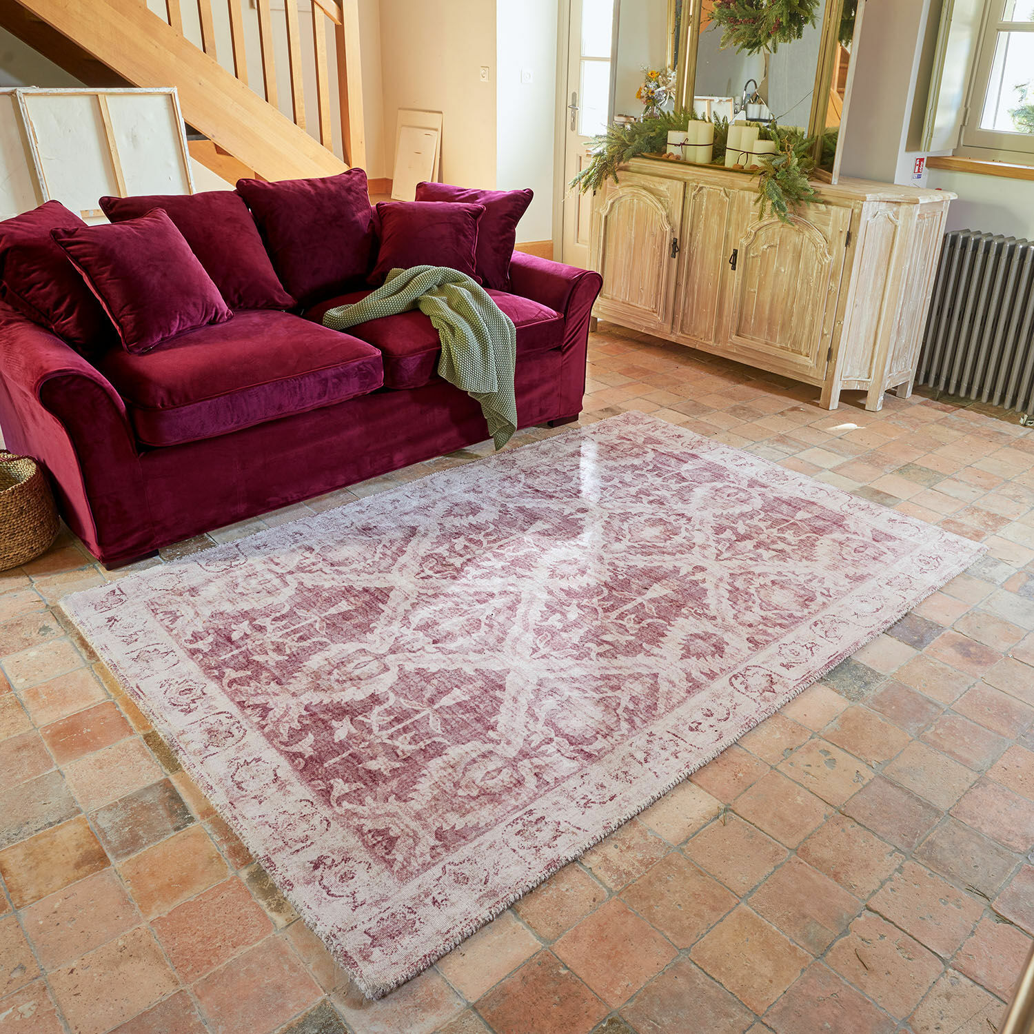 Vloerkleed Mirellis Roze vintage vloerkleed met patroon voor bordeauxrode fluwelen bank en lichte houten kast