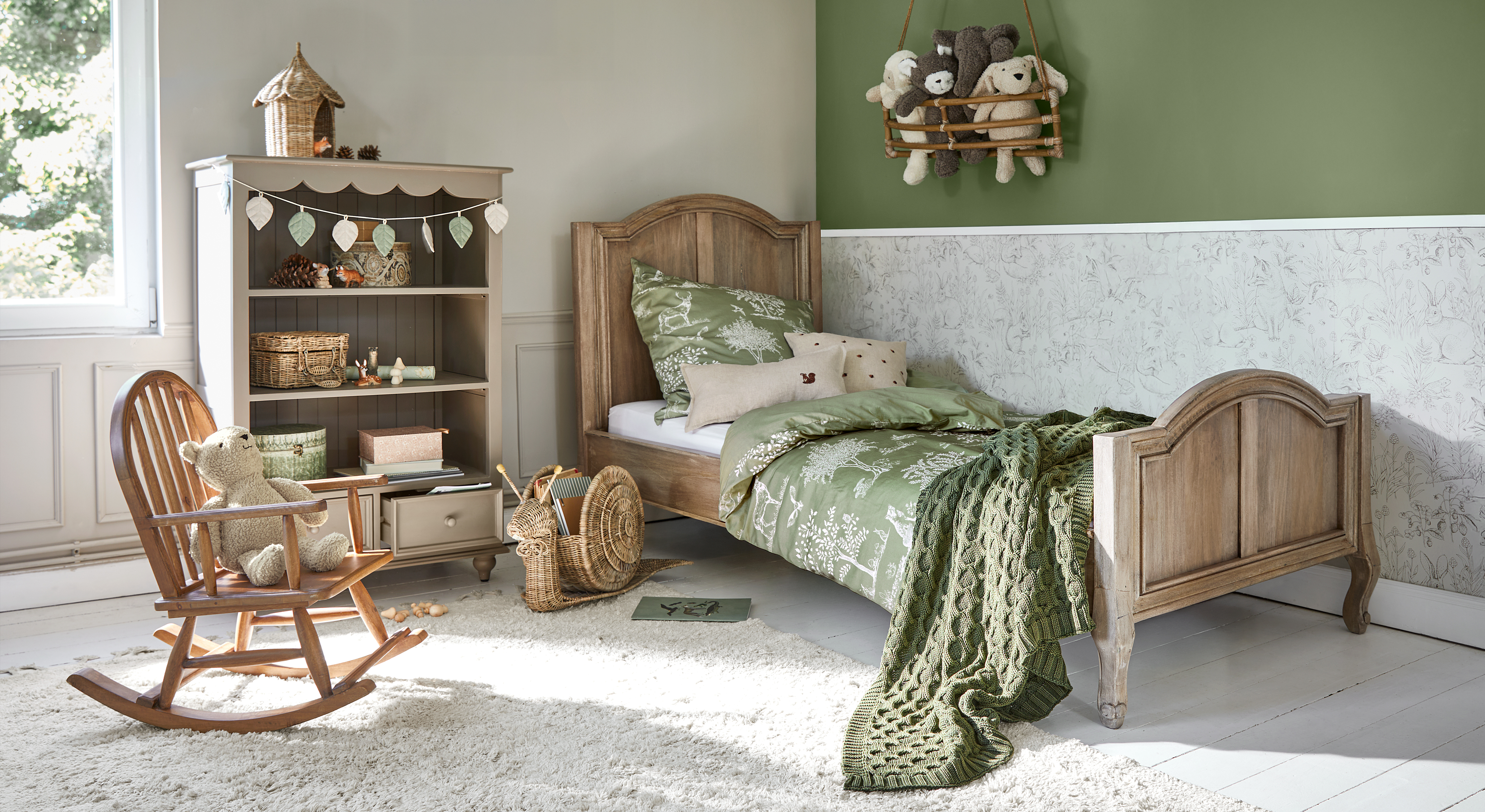 Lit enfant en bois avec literie verte et couverture, chambre chaleureuse avec fauteuil à bascule et peluche