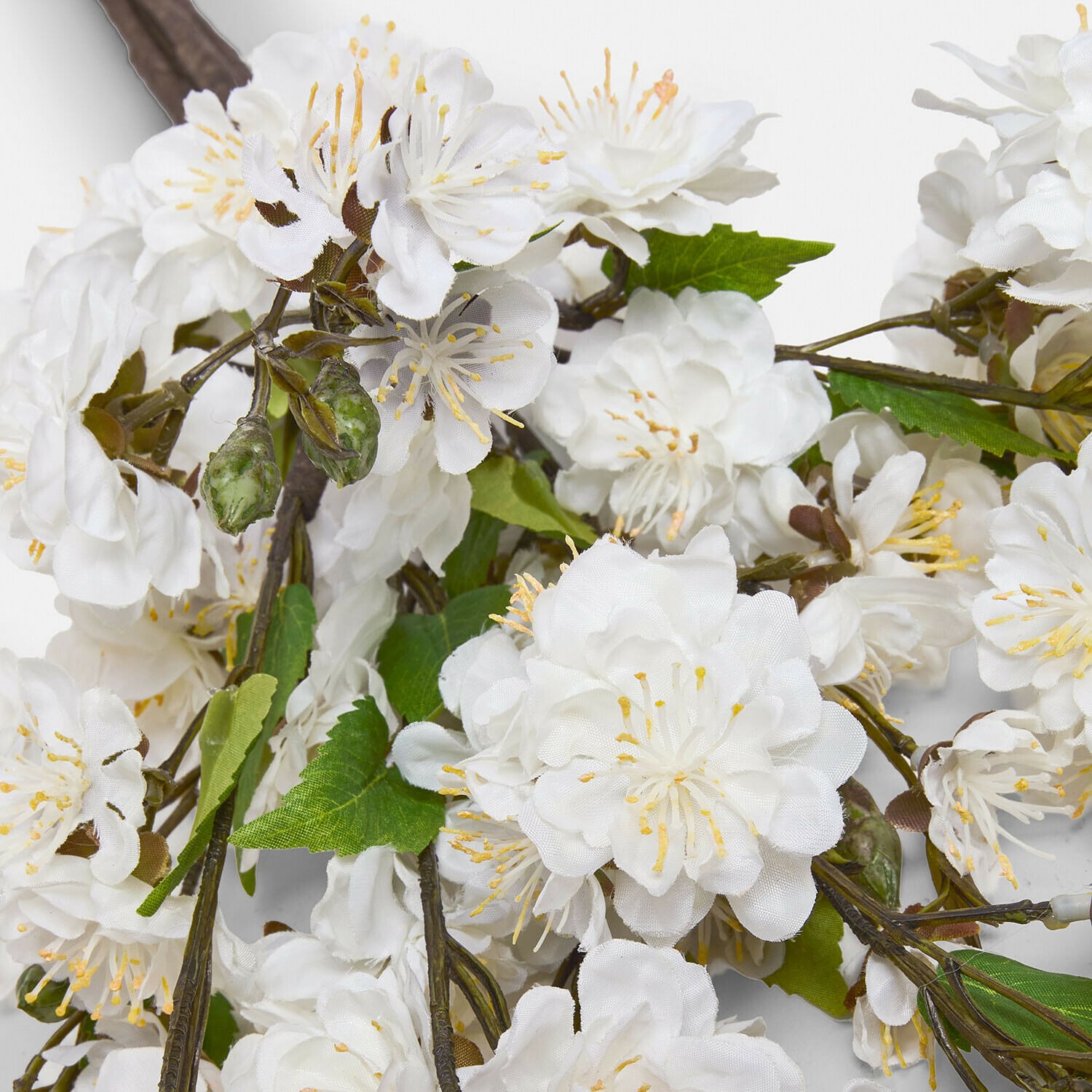 Witte kunstbloemen met groene bladeren aan tak voor interieurdecoratie
