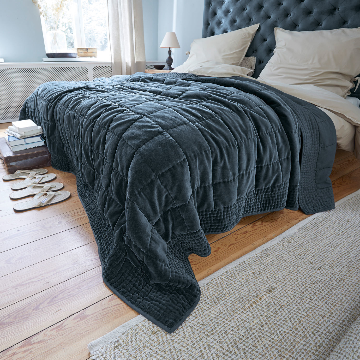 Quilt Arasta Donkerblauwe gewatteerde deken van zacht materiaal op bed in lichte slaapkamer met houten vloer