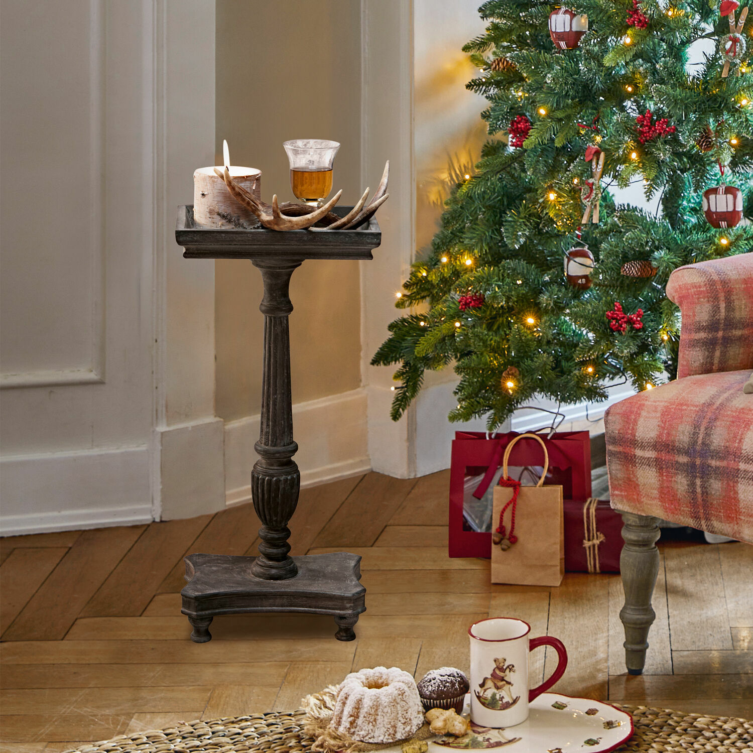 Bijzettafel Caren Donkere houten standaard met kaars en gewei decoratie bij versierde kerstboom en cadeaus