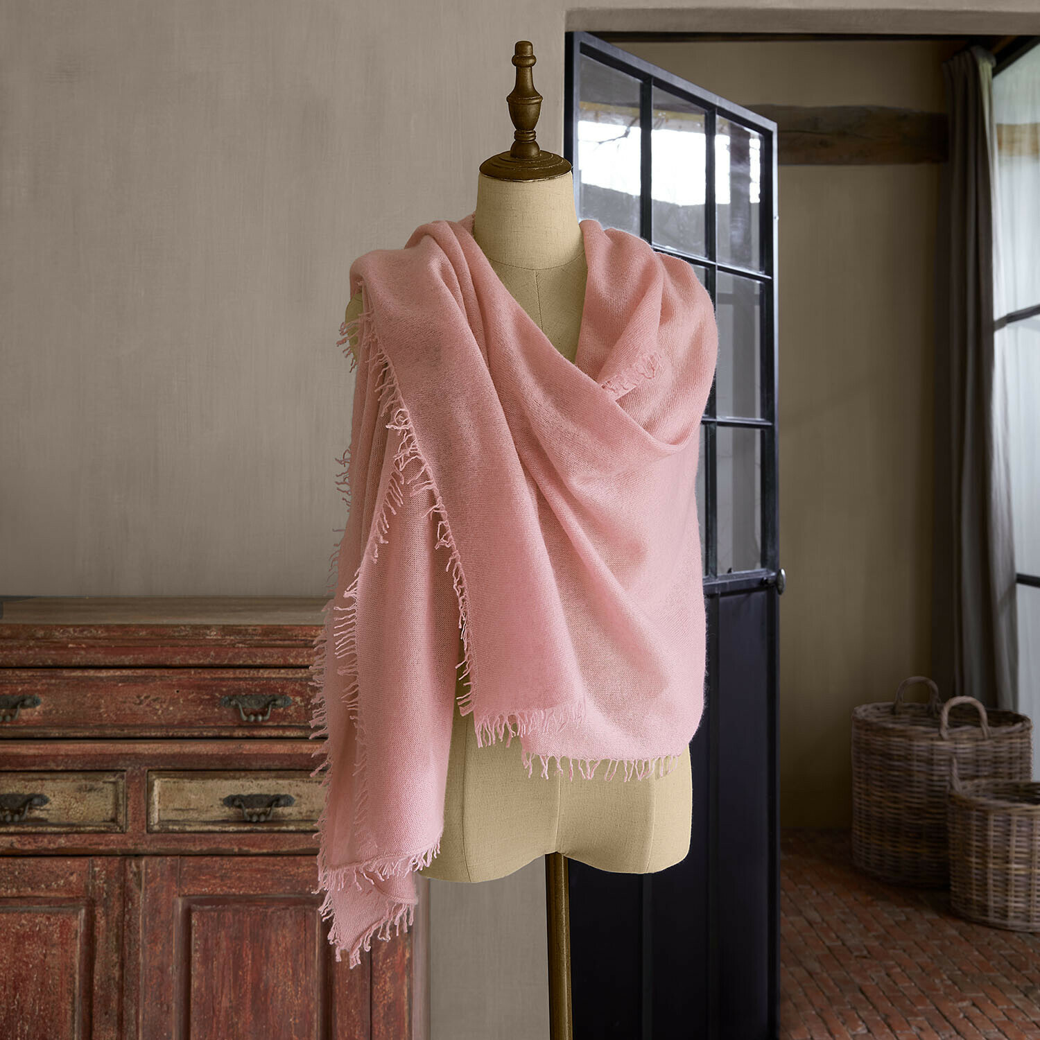 Étole Ulviane Écharpe rose avec franges sur mannequin dans un intérieur rustique, tissu doux pour temps frais