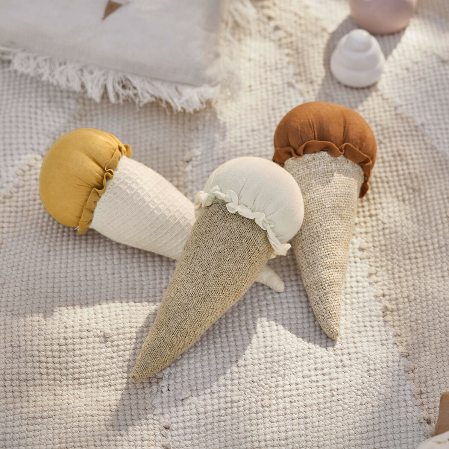 Lot de 3 jouets Cheeklee Trois jouets en tissu en forme de cônes de glace aux tons beige, blanc et marron sur un tapis clair