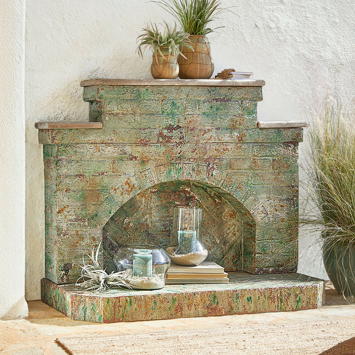 Cheminée décorative en métal vieilli vert et rouille avec bougies et plantes décoratives