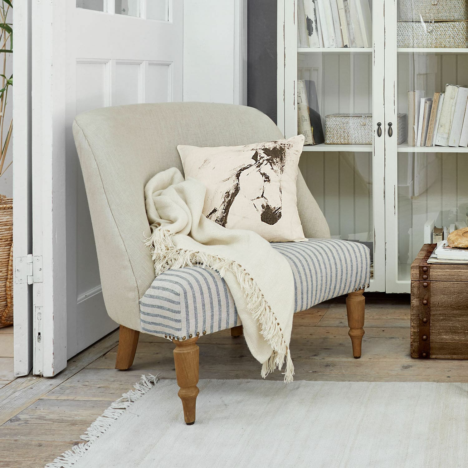 Fauteuil Maplewood Canapé bicolore beige et rayé avec coussin imprimé cheval et plaid crème dans un salon lumineux