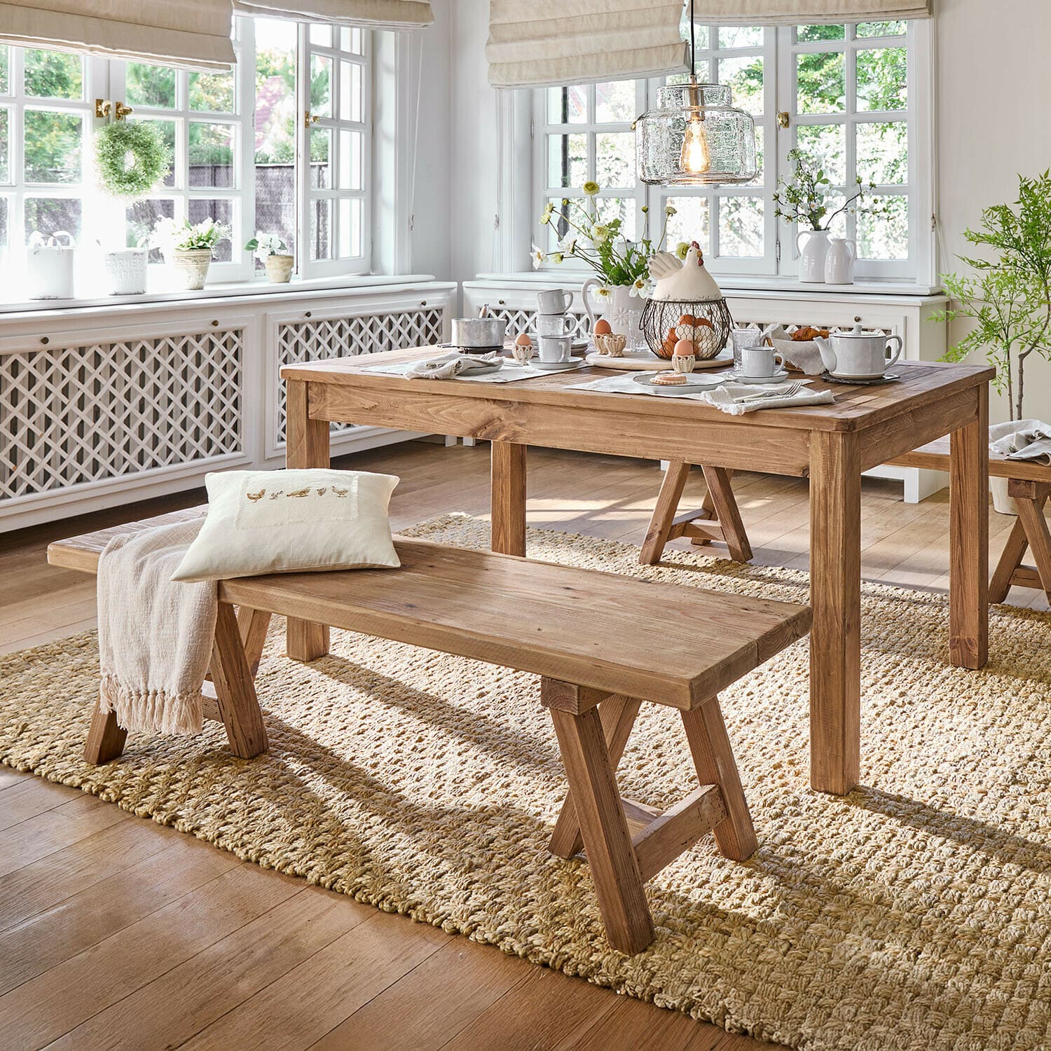 Banc Amherst Salle à manger avec table et banc en bois sur tapis naturel, intérieur lumineux avec grandes fenêtres