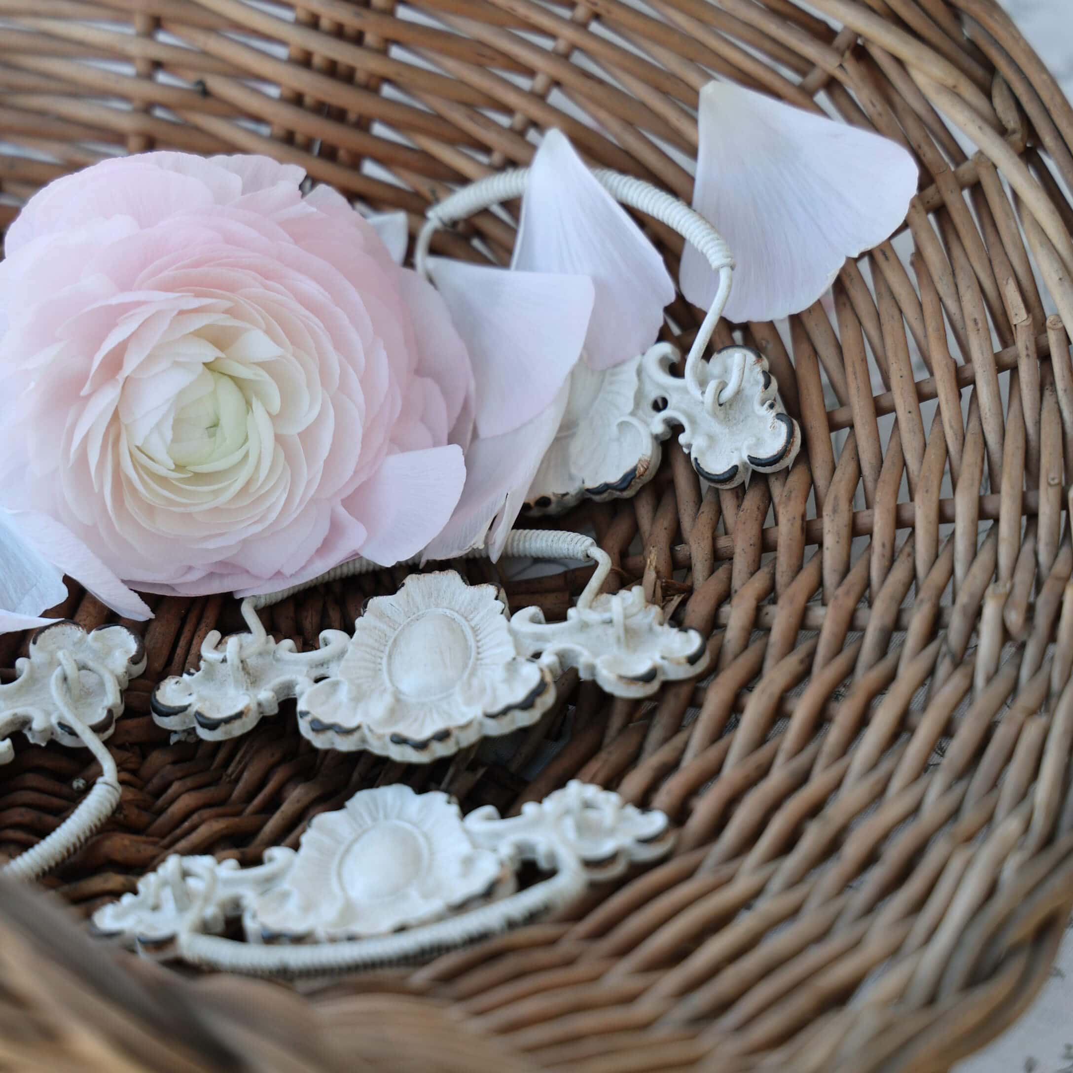 Fleur rose délicate et poignées en métal blanc dans un panier en osier, décoration intérieure vintage