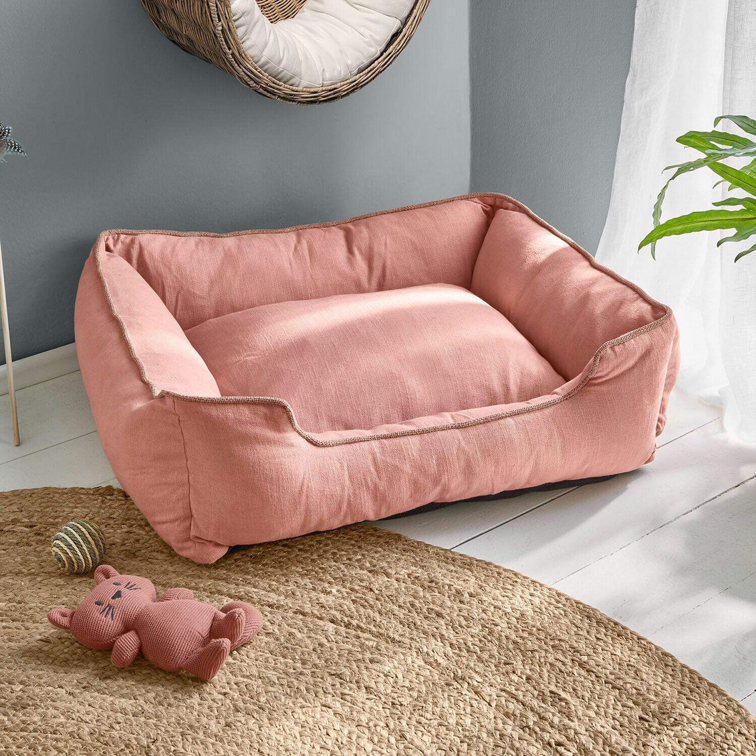 Lit pour animaux Ivandelle Panier pour chien rose en tissu doux sur sol clair avec jouet chat et tapis en jute