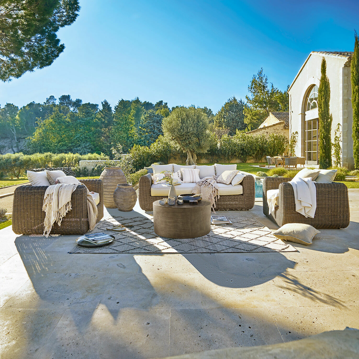 Salon de jardin Bogdanne Ensemble de mobilier de jardin en rotin marron avec coussins crème sur terrasse ensoleillée avec vue sur jardin