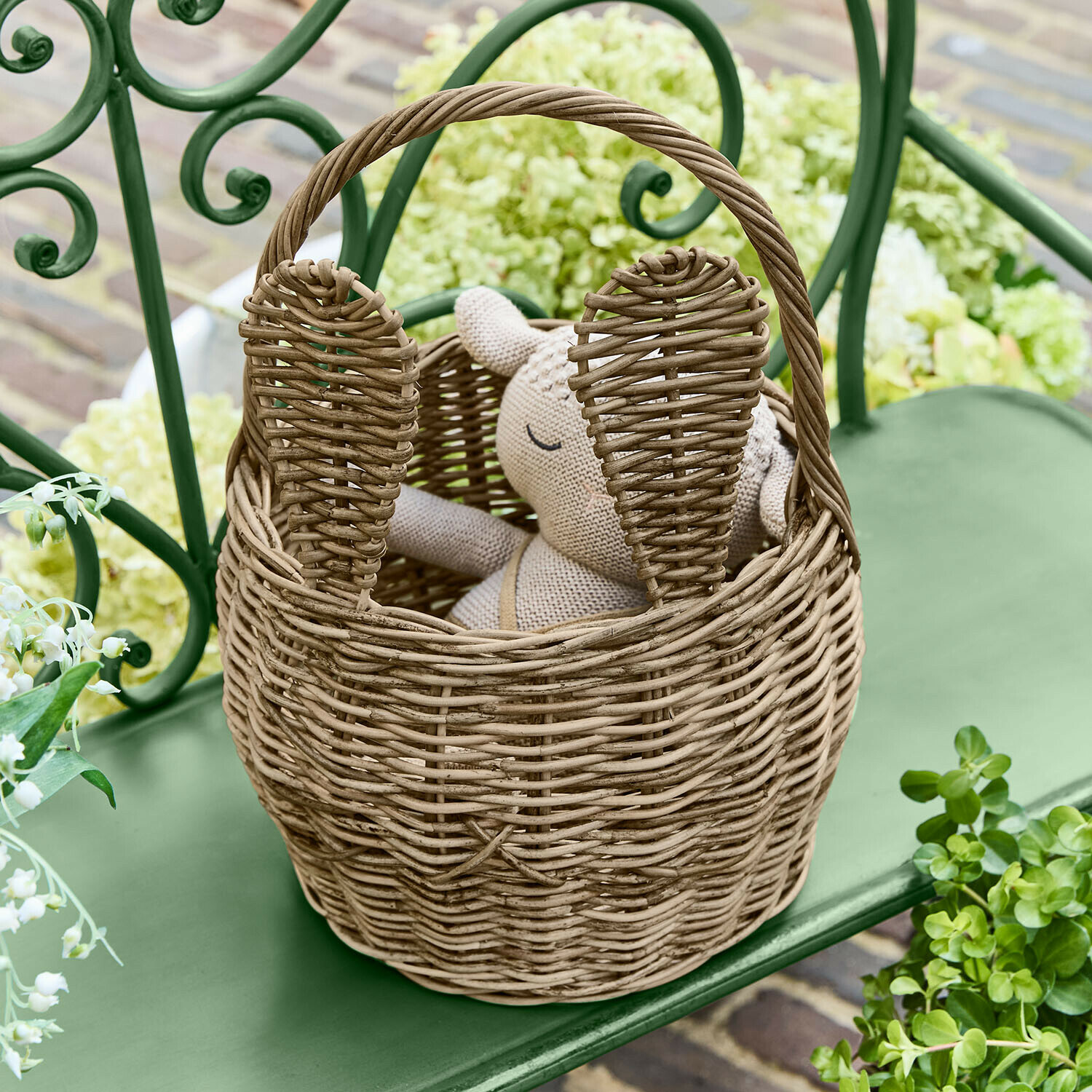 Konijnenmand Whimsywood Natuurlijke rieten mand in konijnenvorm met oren, op een groene tuinbank geplaatst