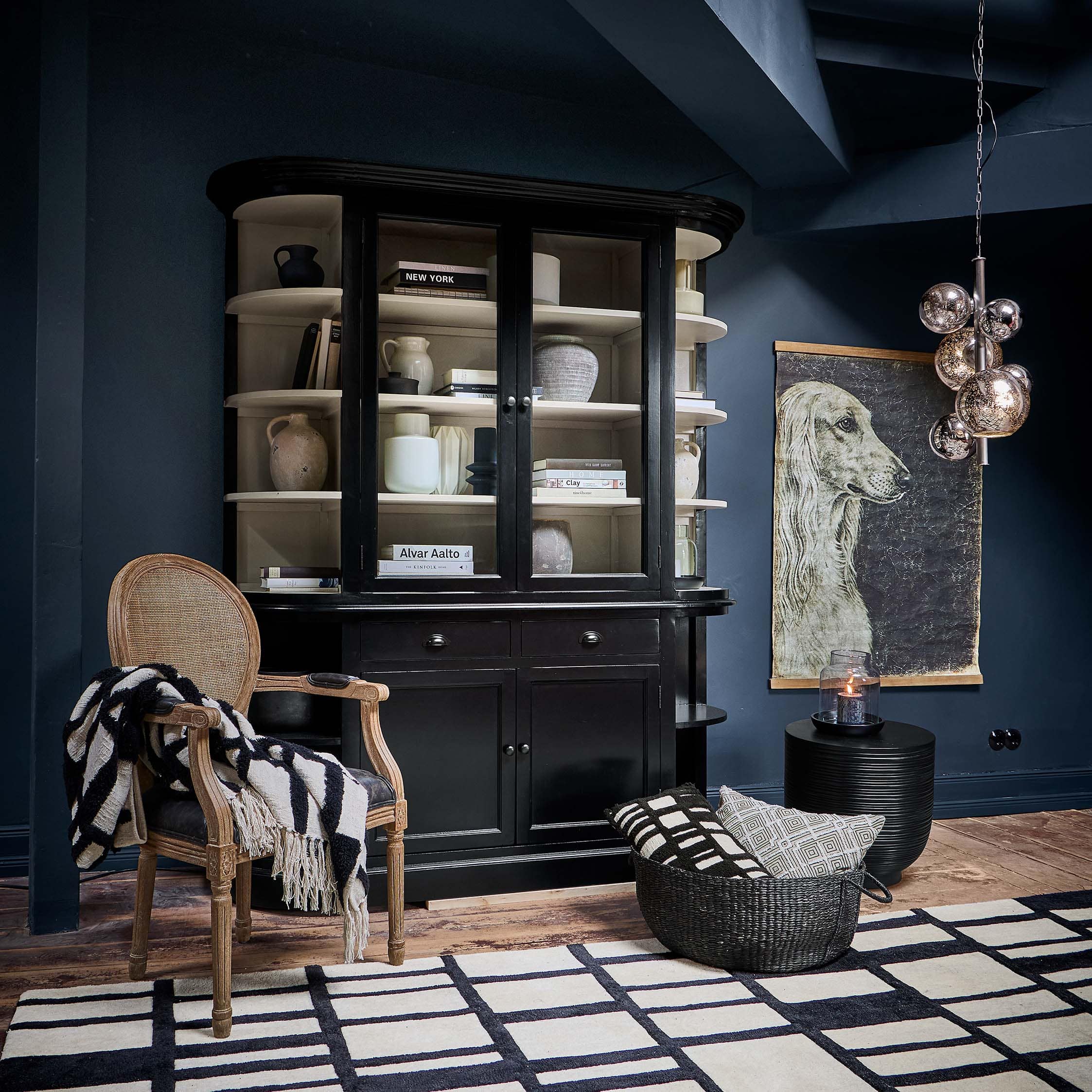 Vitrine en bois noir avec portes vitrées et étagères décorées dans un style vintage