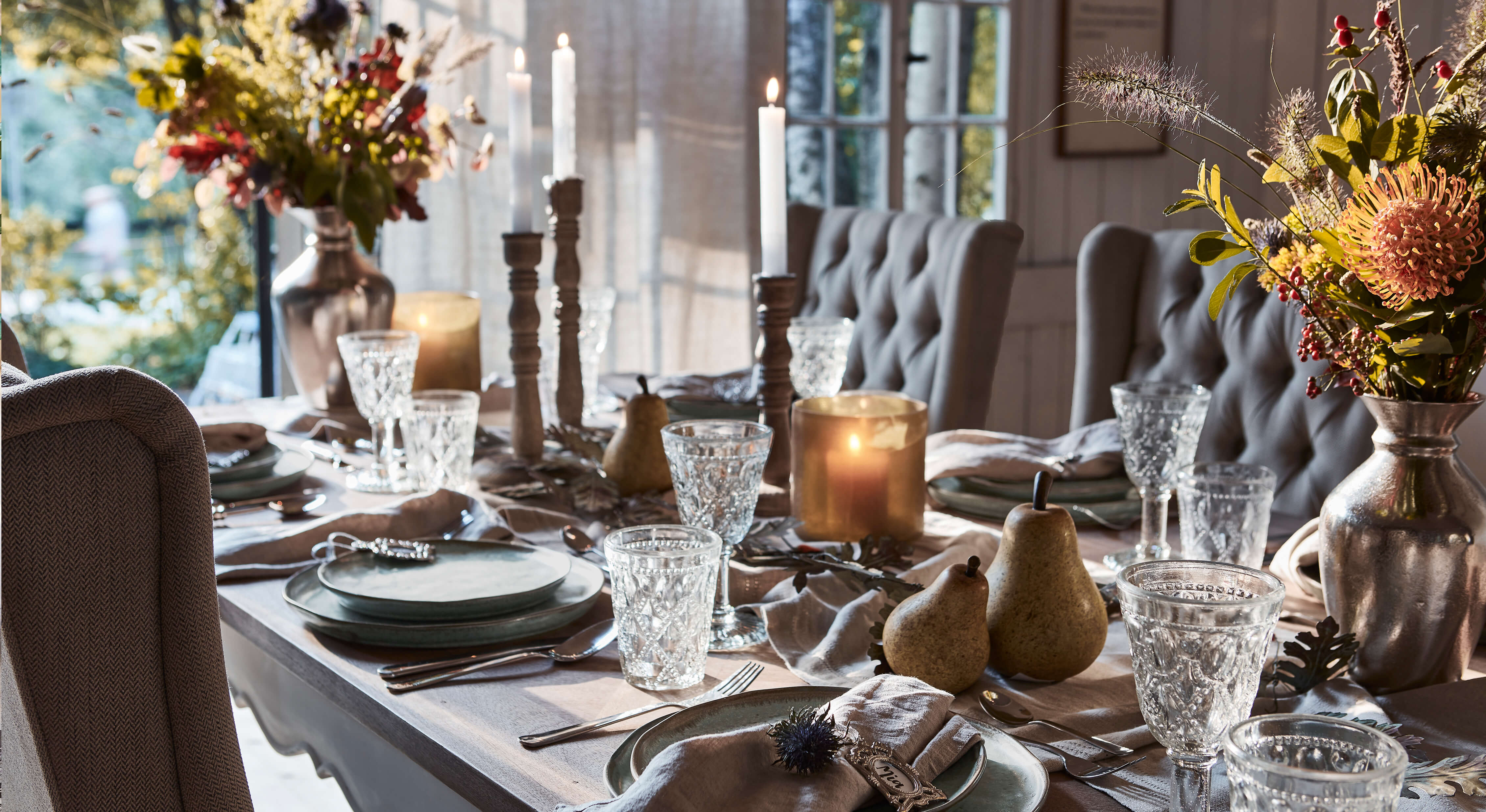 Elegant gedekte tafel met grijze borden, kristallen glazen en kaarsen in een gezellige omgeving